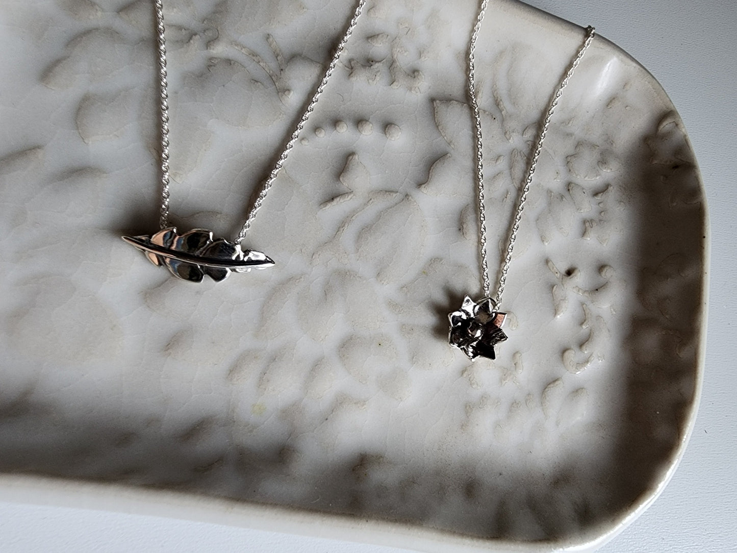 Tiny flower pendant hanging from a dainty silver chain