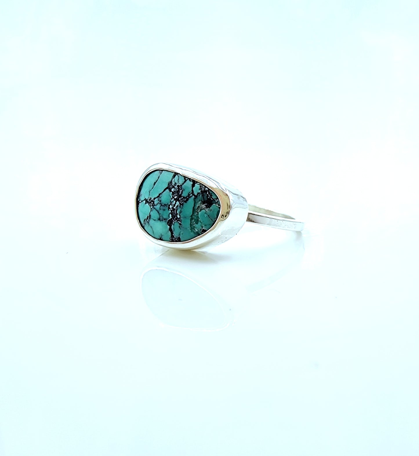Silver ring with a turquoise stone on a light blue background