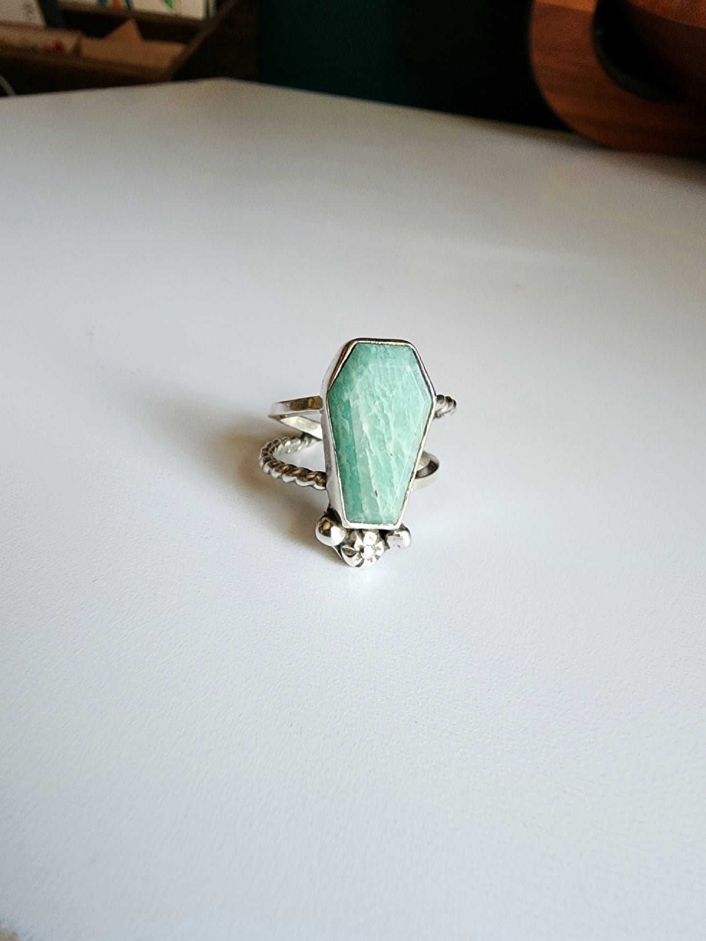 Amazonite coffin stone ring size 7 1/4 split shank with patterned twisted silver on top right and bottom left, square profile on top left and bottom right flower and small granulations on the left and right of small flower at bottom of stone.