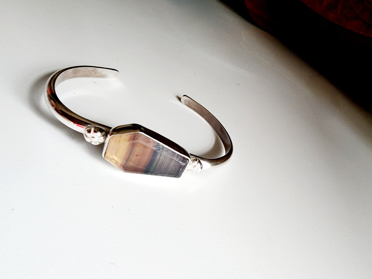 Fluorite coffin stone cuff with small botanical flowers on the left and right mounted on a sterling silver cuff