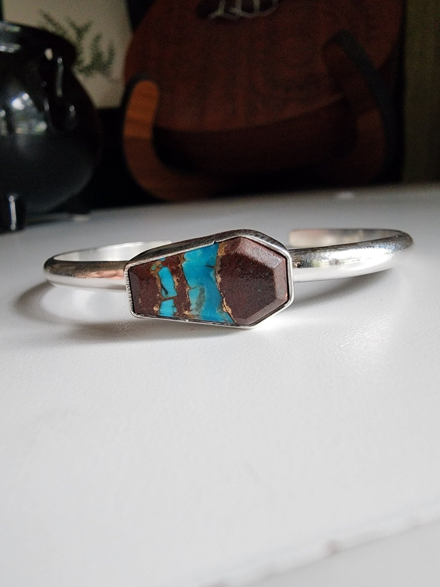 a coffin shaped stone that is blue and red (lave copper turquoise) mounted on a simple sterling silver cuff