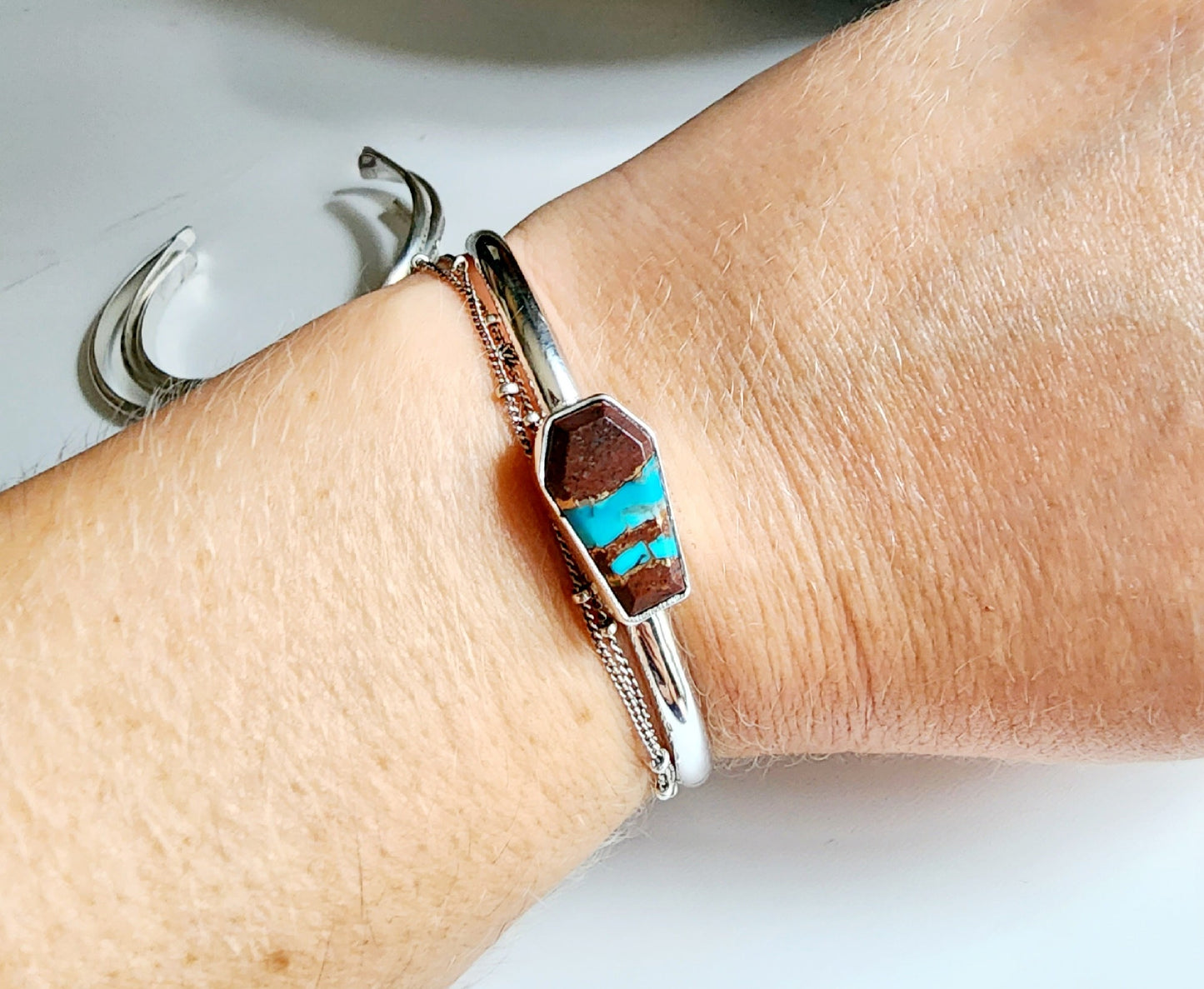 a coffin shaped stone that is blue and red (lave copper turquoise) mounted on a simple sterling silver cuff