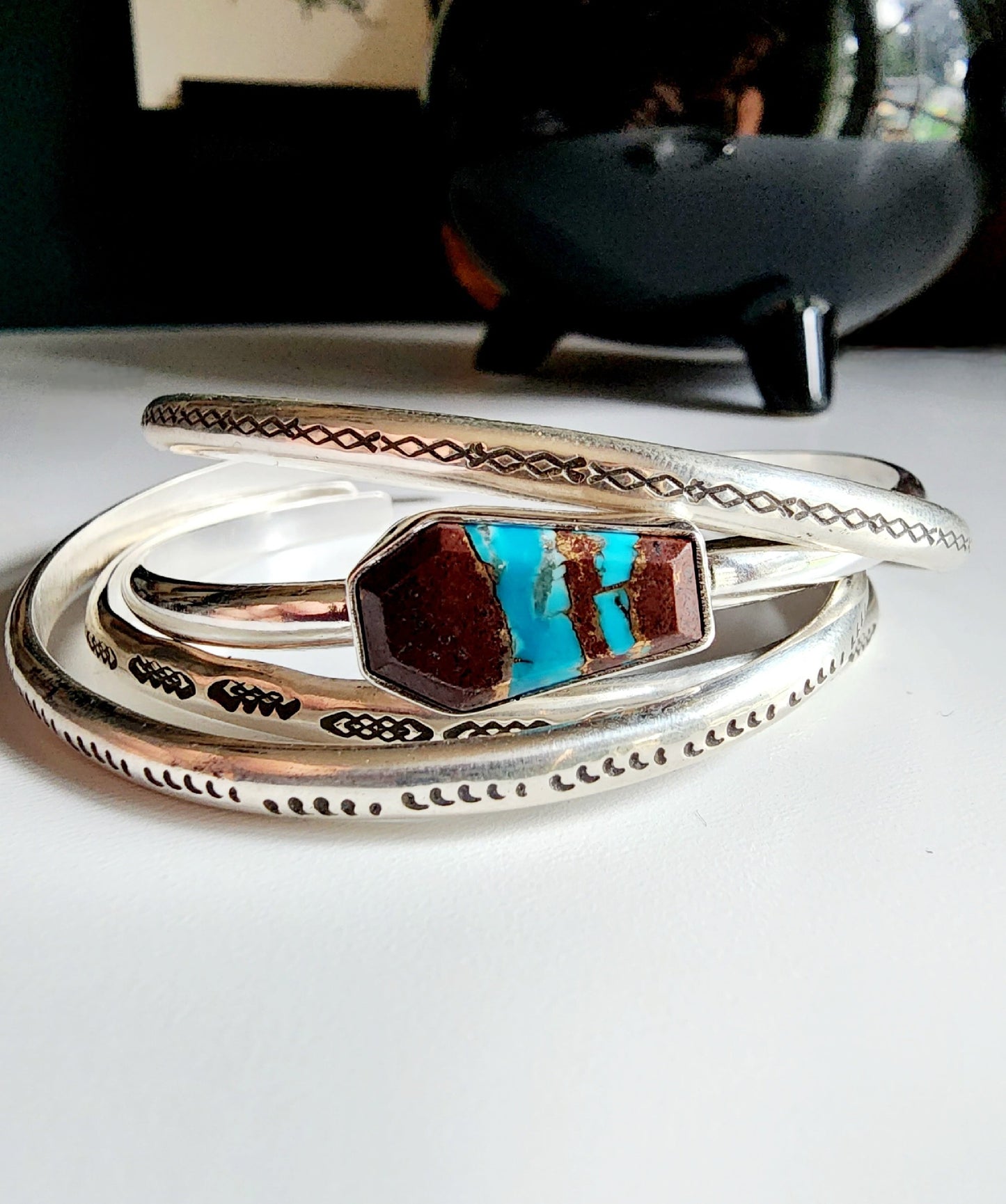 a coffin shaped stone that is blue and red (lave copper turquoise) mounted on a simple sterling silver cuff