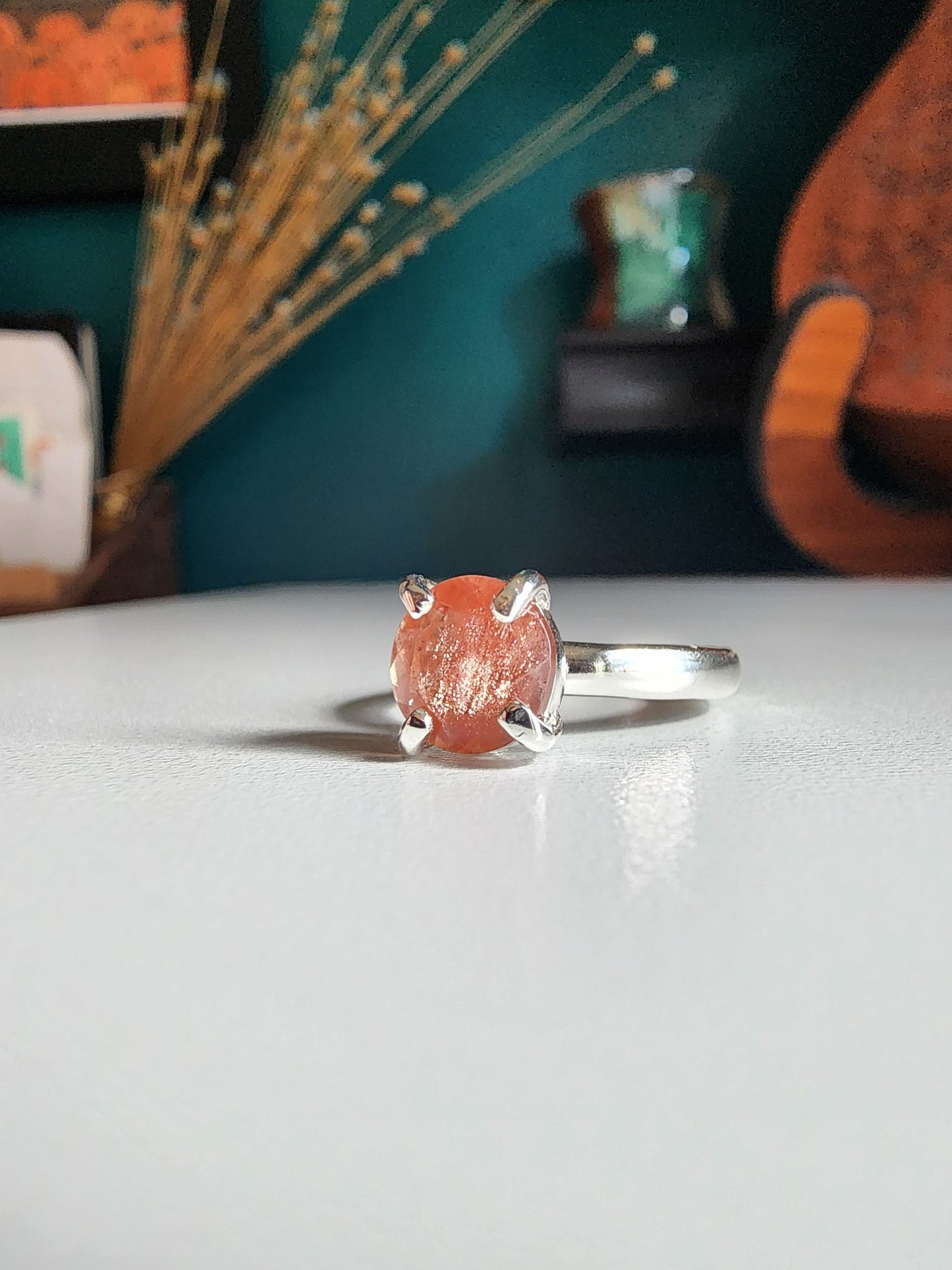 Oregon sunstone solitaire ring with pink and orange colors reflected through the stone, 4 prong set on a thick silver band for resilience