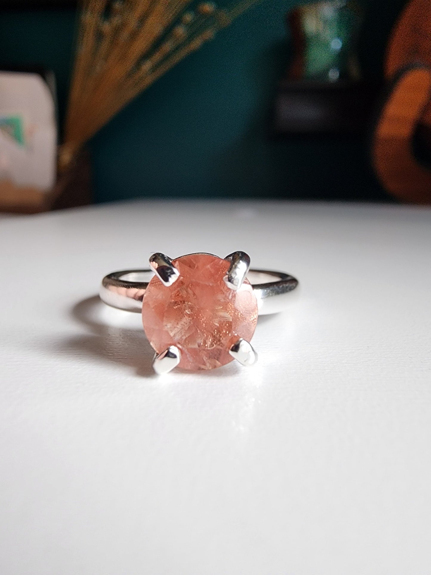 Oregon sunstone solitaire ring with pink and orange colors reflected through the stone, 4 prong set on a thick silver band for resilience 