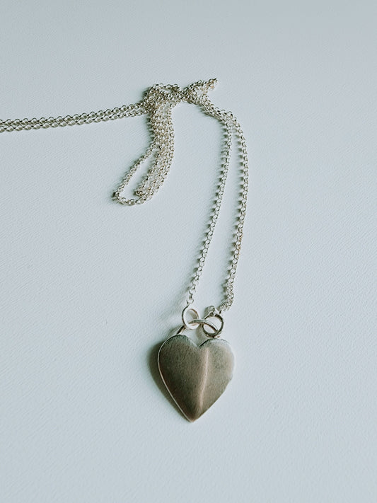 Simple heart necklace mounted on a 18 inch sterling silver necklace, Simple heart rests at the bottom of silver necklace. Minimalist design, pendant is 8mm by 5mm