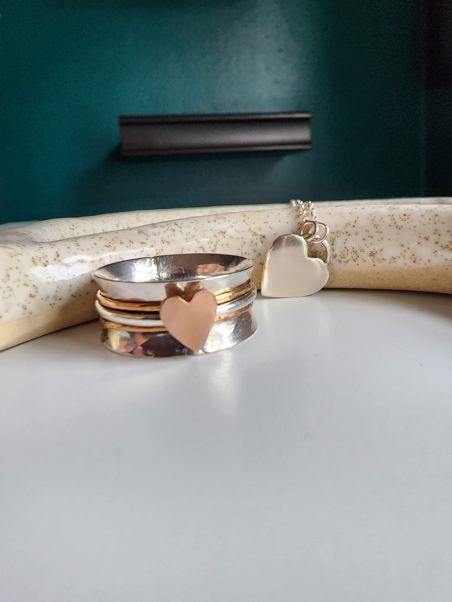Silver textured wide band ring with three bands top band gold, middle band silver with a rose gold heart, bottom band is gold. Three bands mounted on a wide ring that spin freely, perfect for spinning of rings