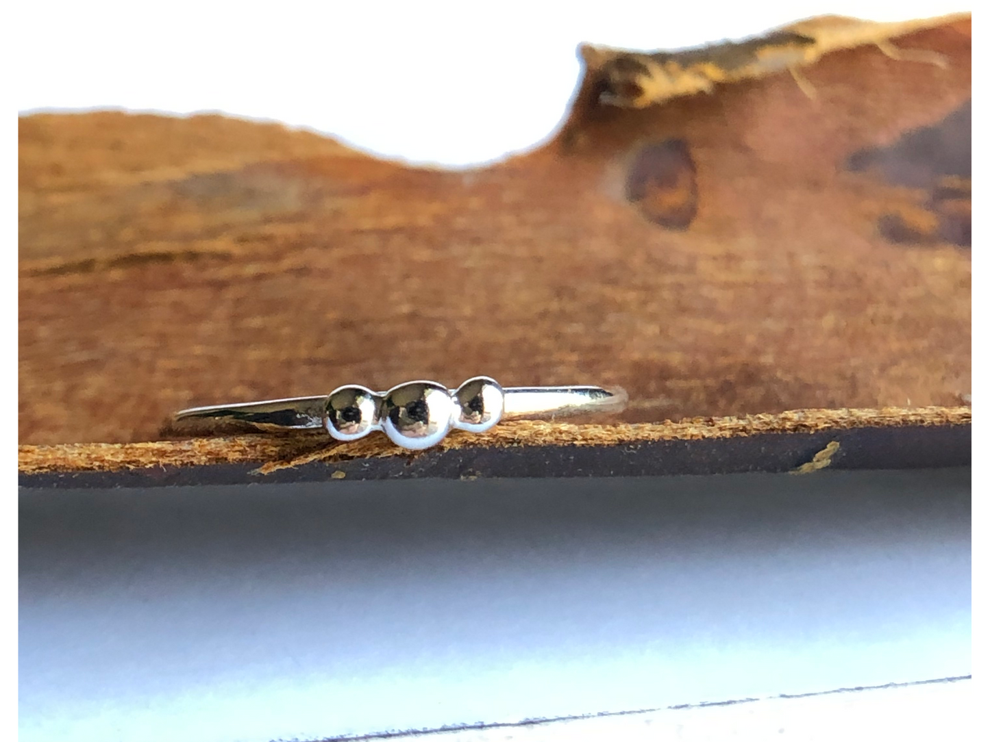 small dots of silver three in total as the focal of this rounded band ring.