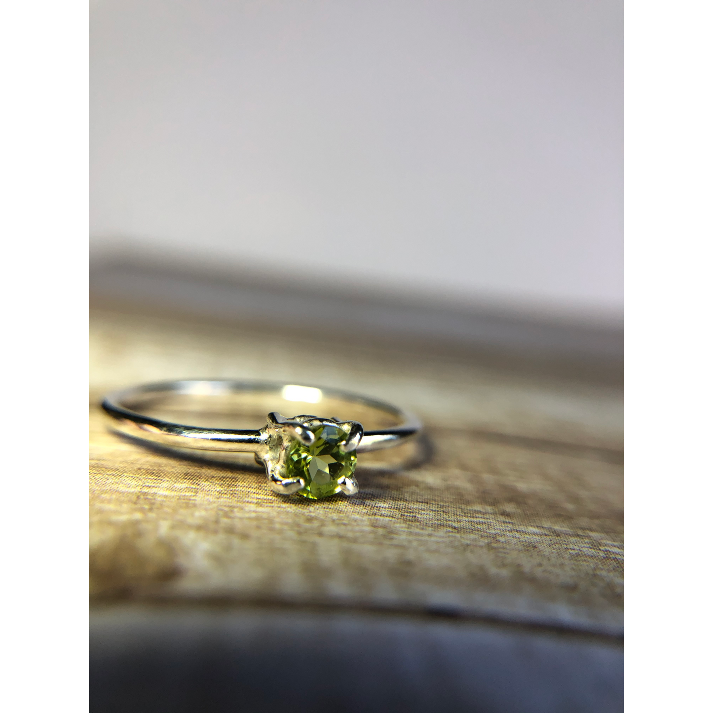 small green gemstone with simple band connecting to left and right side of stone.