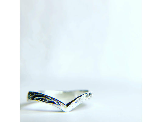 Patterned silver ring with chevron shape.