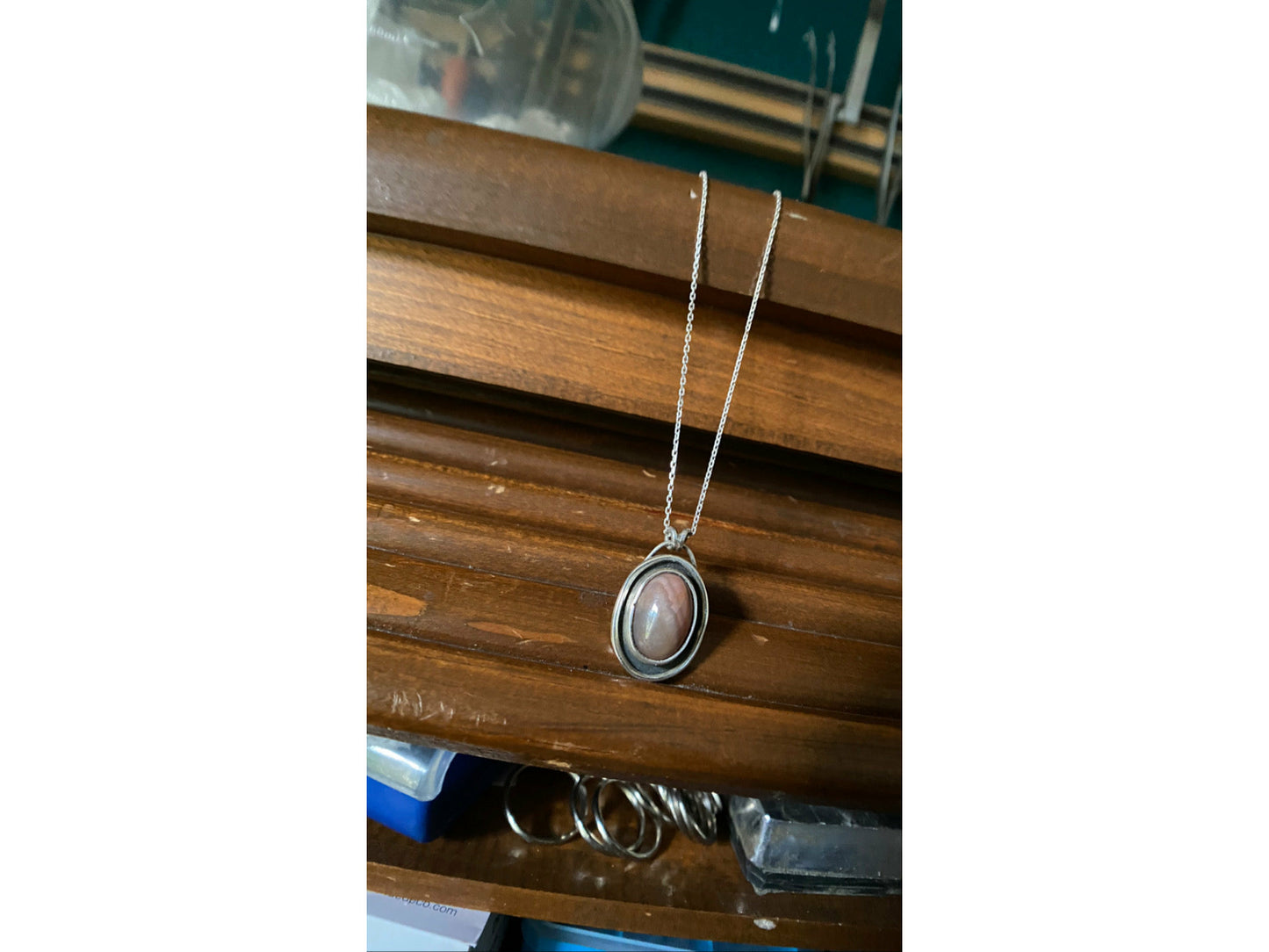 Oval pink stone with silver surround encircling stone, mounted on a 18 ich sterling silver necklace this is a choker style chain.