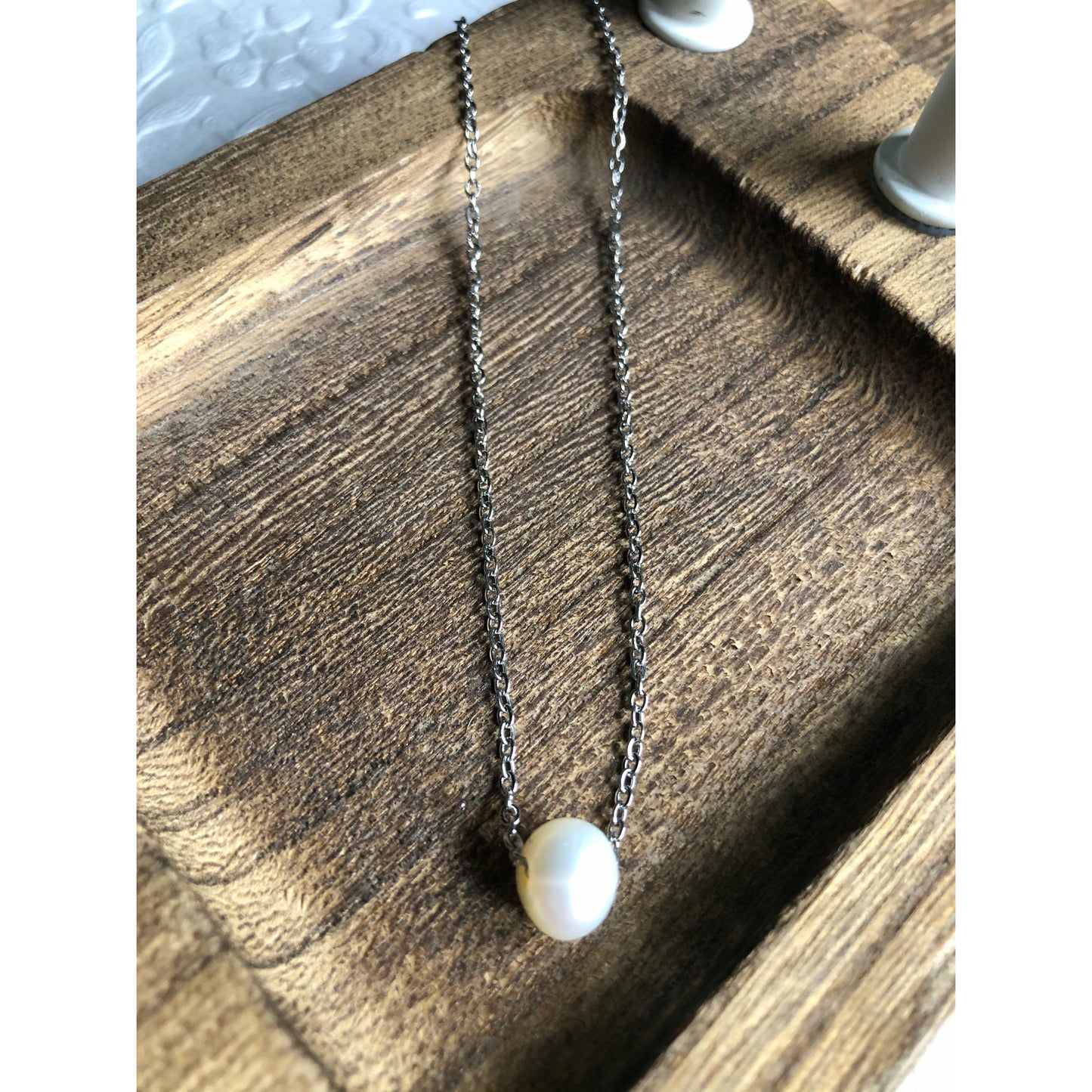 Small simple pearl with the chain of the necklace fed through it