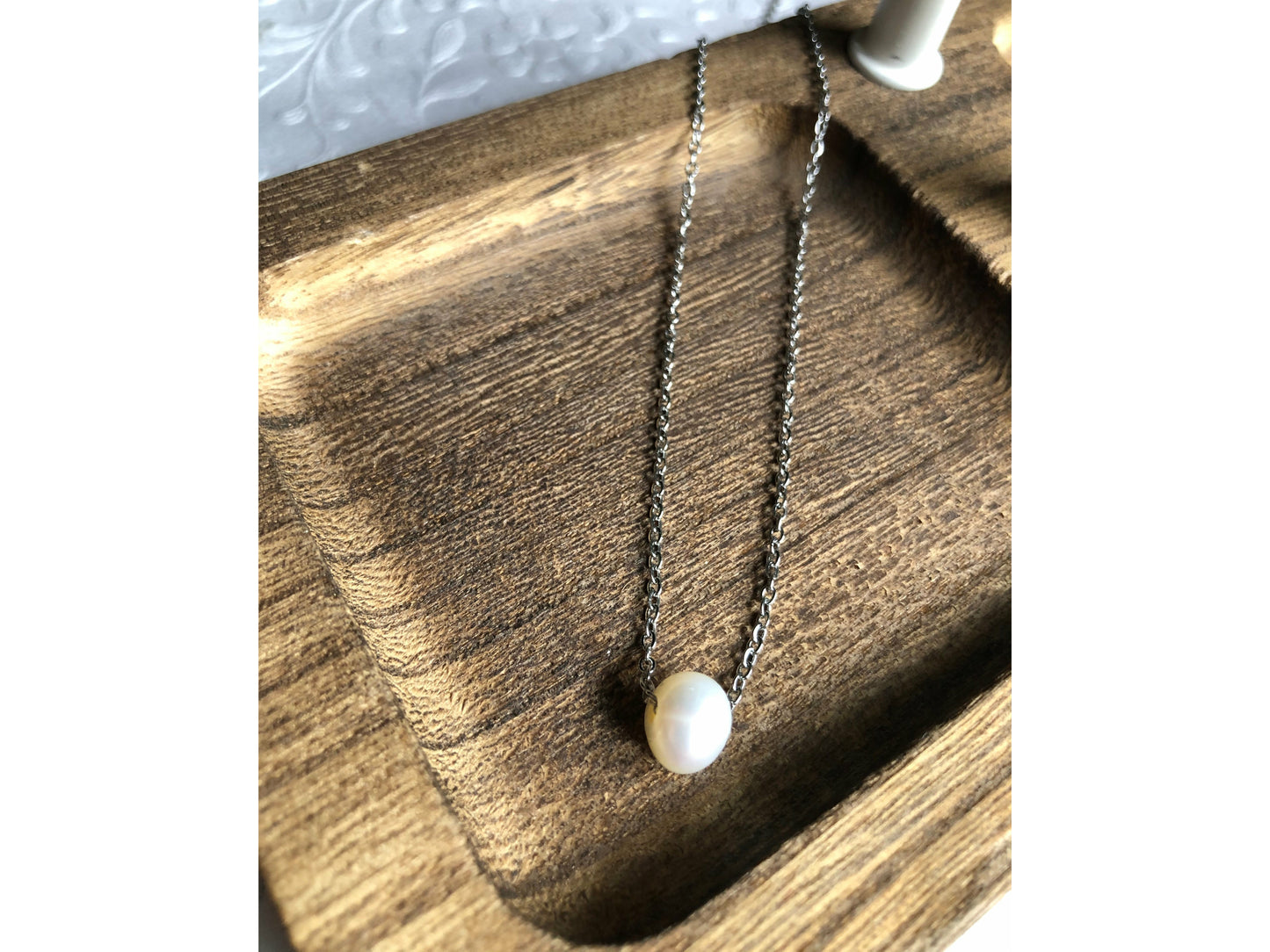 Small simple pearl with the chain of the necklace fed through it