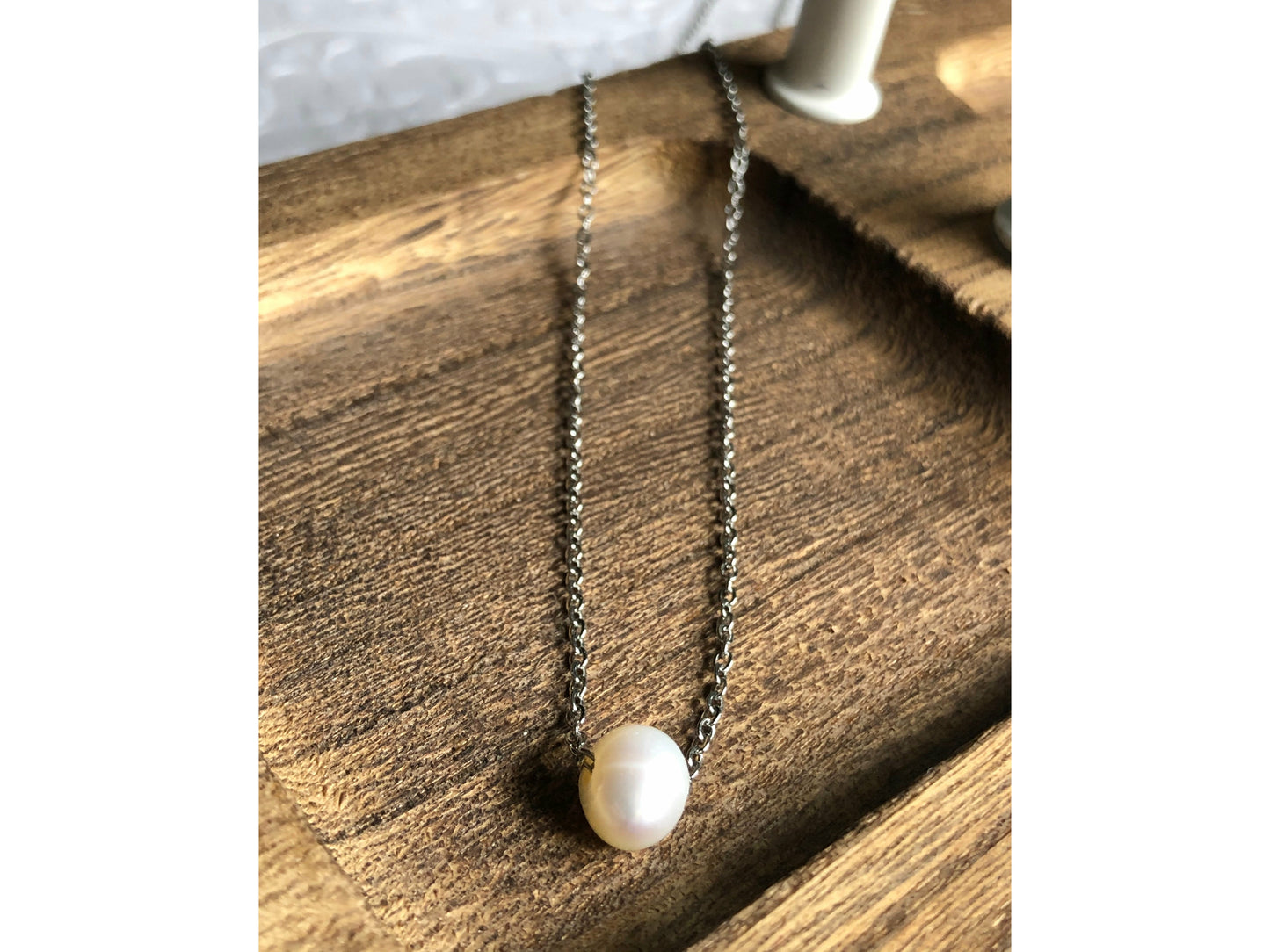 Small simple pearl with the chain of the necklace fed through it