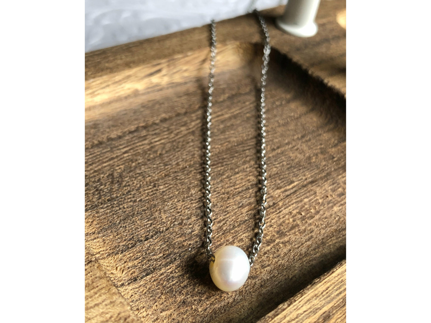 Small simple pearl with the chain of the necklace fed through it