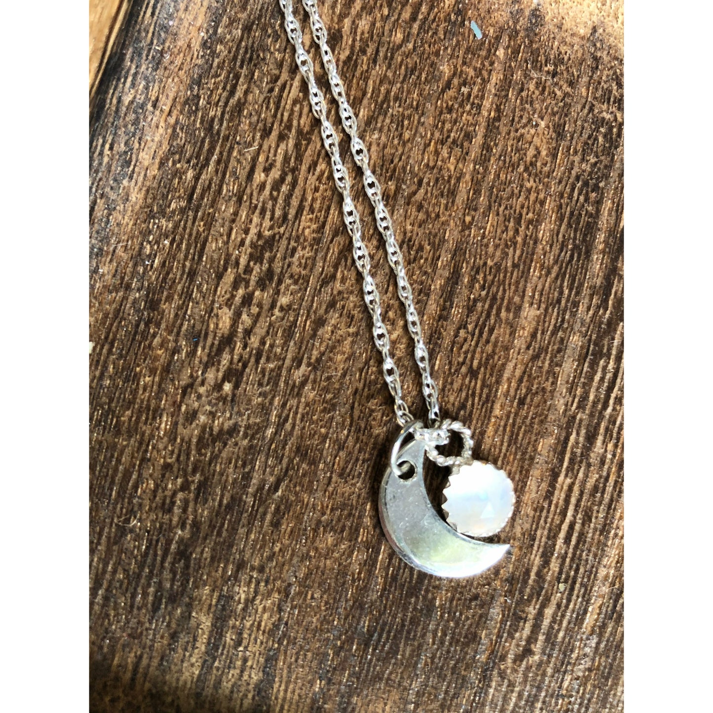 Small sliver of a moon mounted on a stainless steel chain