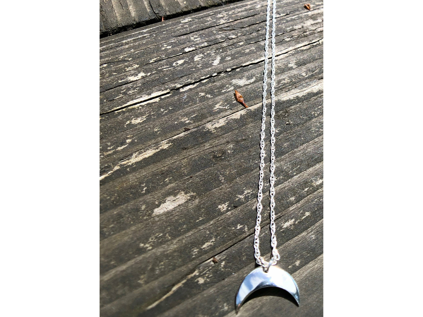 Sterling silver moon shape pointed downward mounted on a stainless steel chain