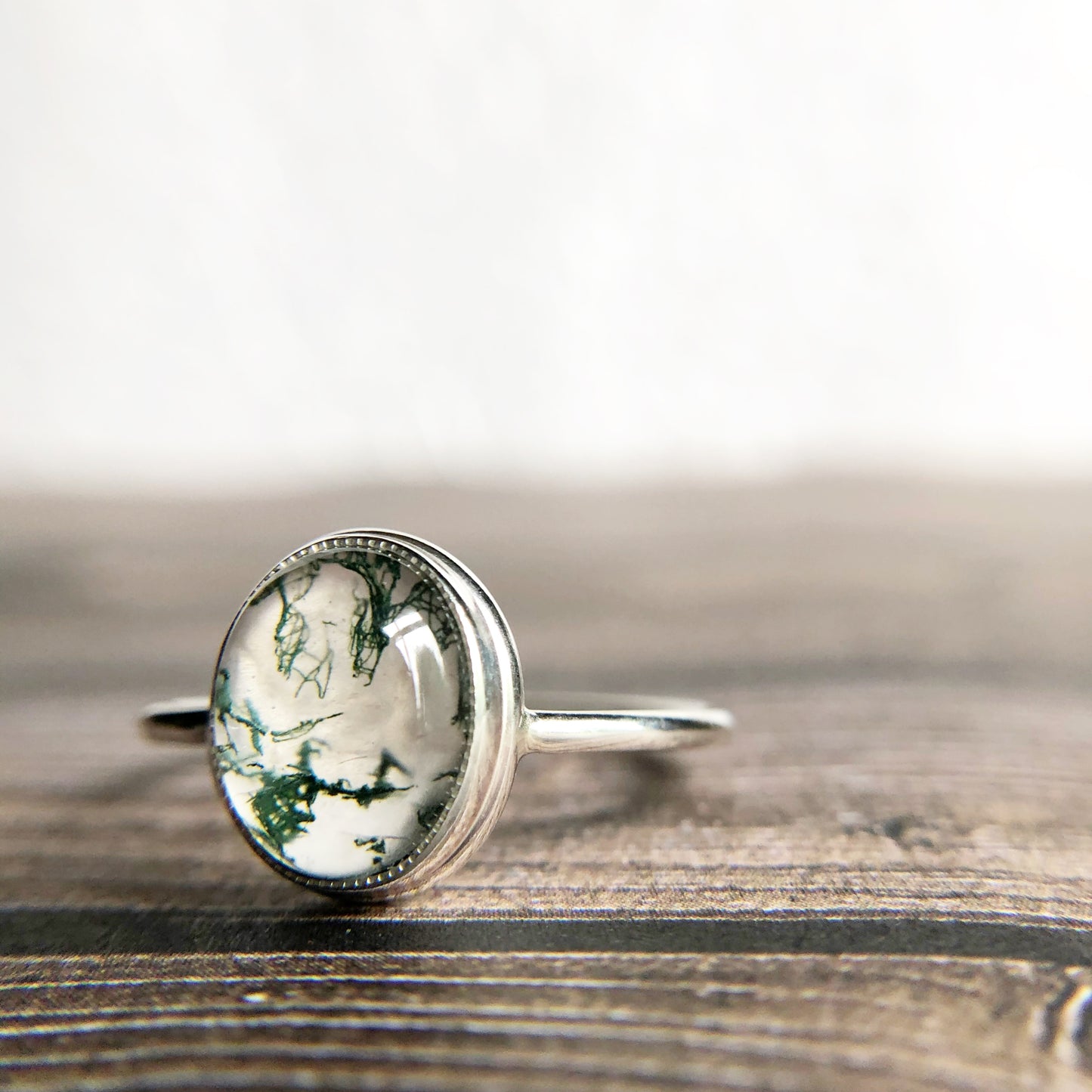 Tiny dots of moss surrounded in quartz, open back bezel with simple silver band