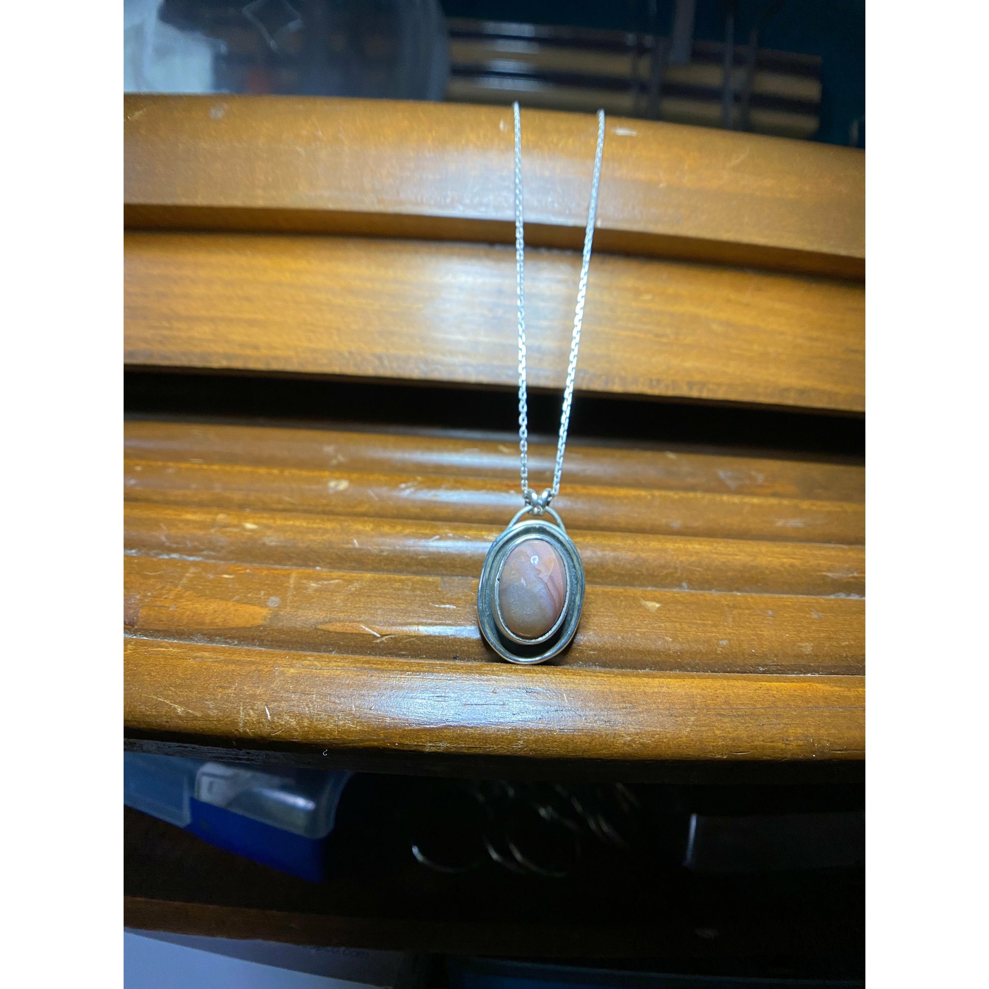 Oval pink stone with silver surround encircling stone, mounted on a 18 ich sterling silver necklace this is a choker style chain.