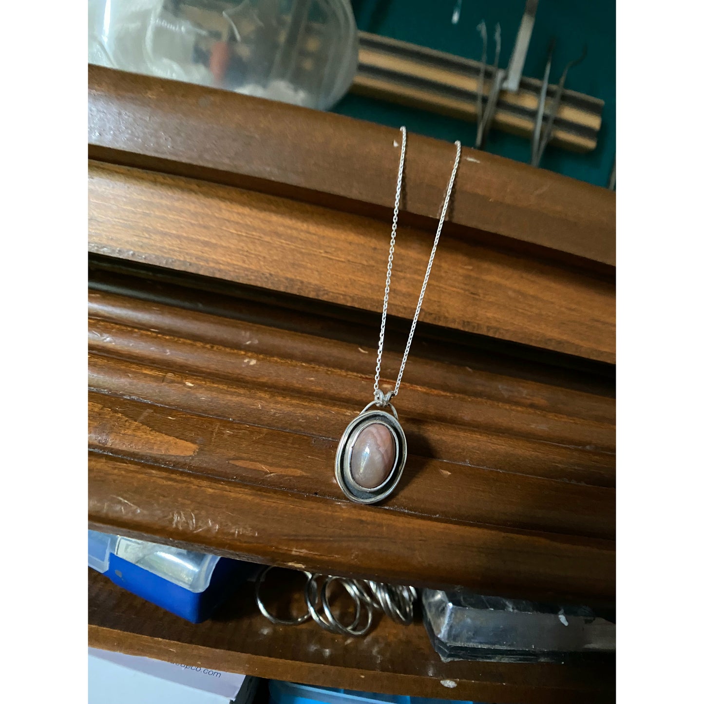Oval pink stone with silver surround encircling stone, mounted on a 18 ich sterling silver necklace this is a choker style chain.