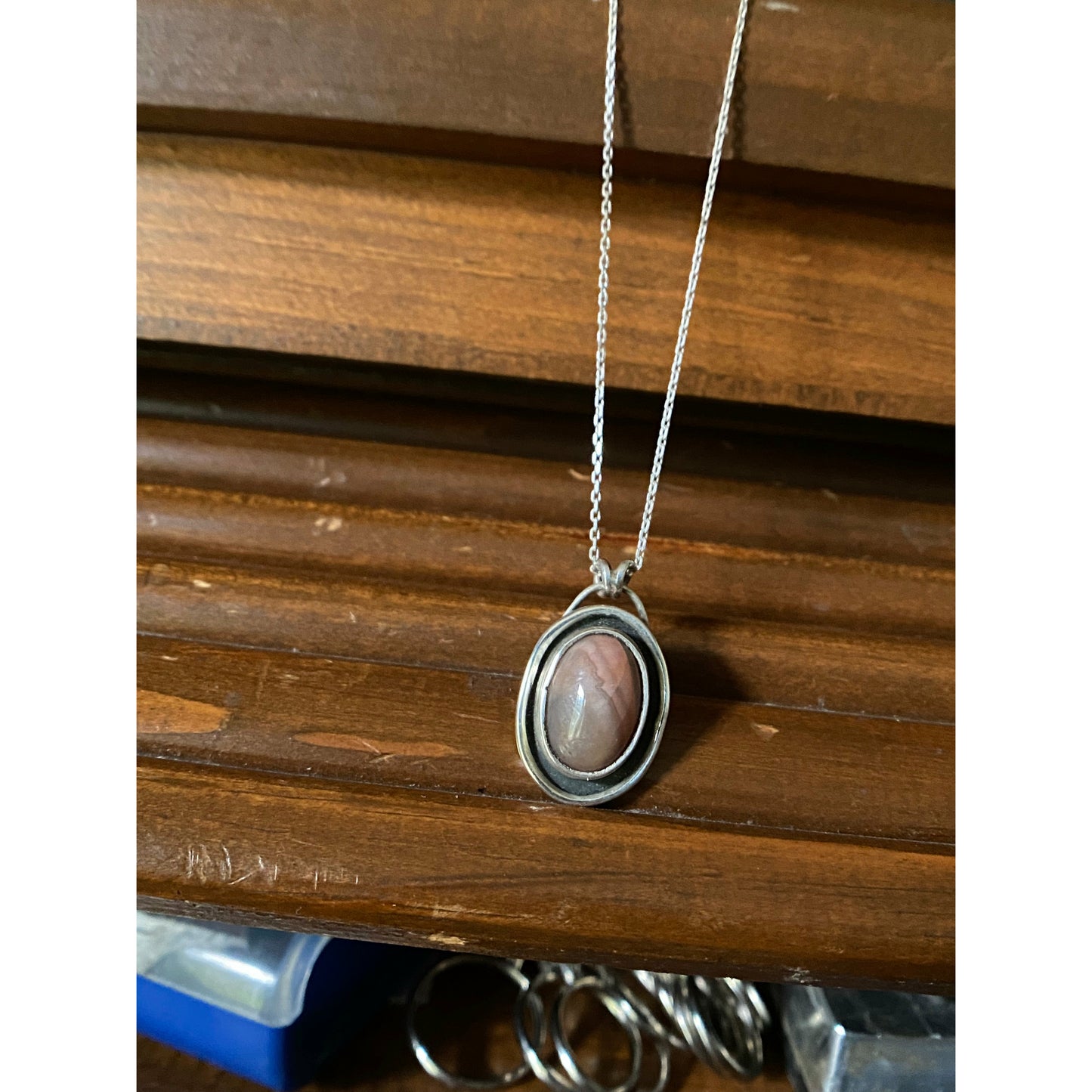 Oval pink stone with silver surround encircling stone, mounted on a 18 ich sterling silver necklace this is a choker style chain.