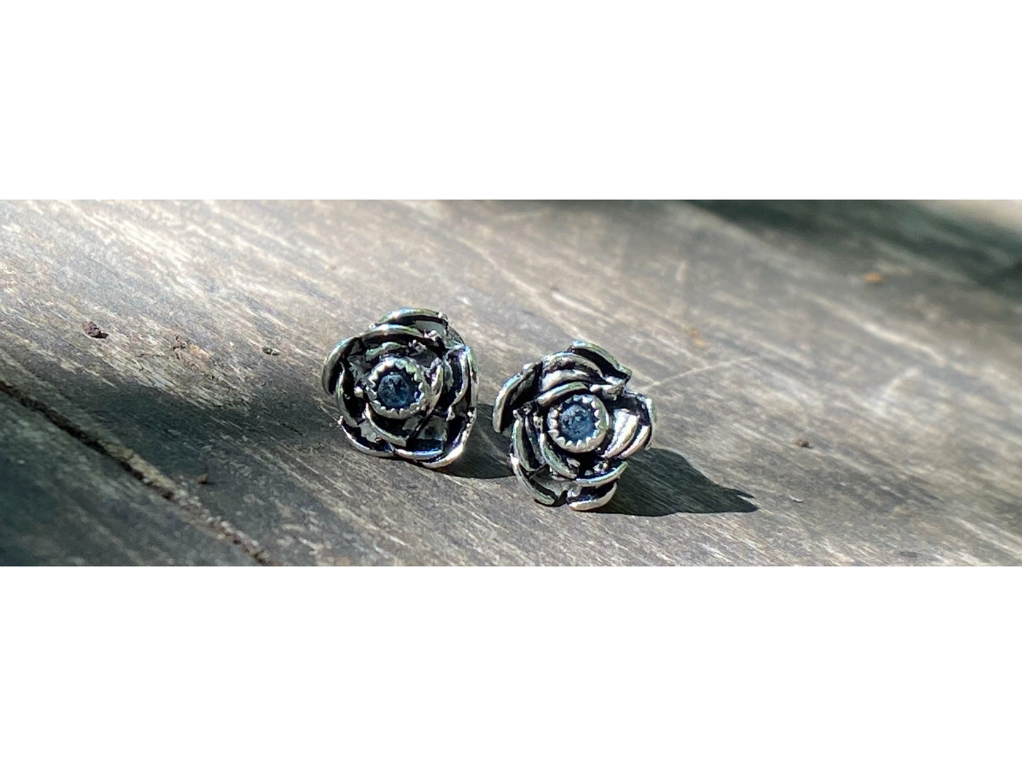 Rose wrapped silver around a small sapphire looking like the center of the bloom.