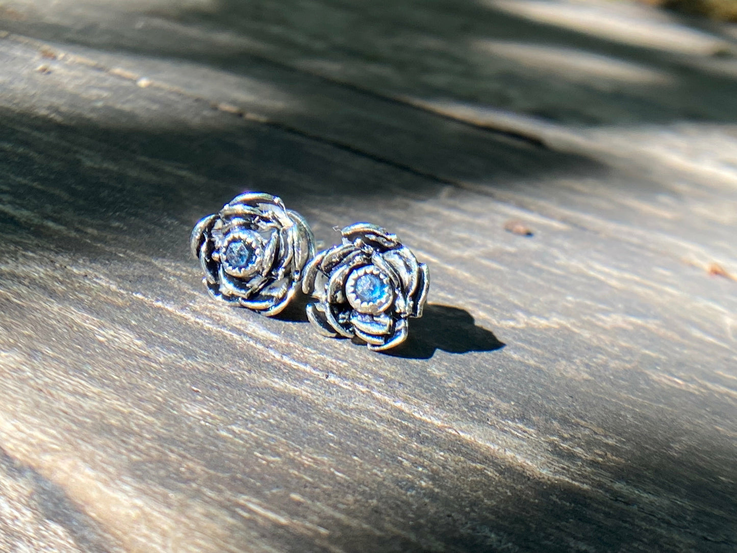Rose wrapped silver around a small sapphire looking like the center of the bloom.