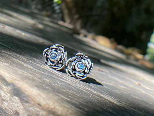 Rose wrapped silver around a small sapphire looking like the center of the bloom.