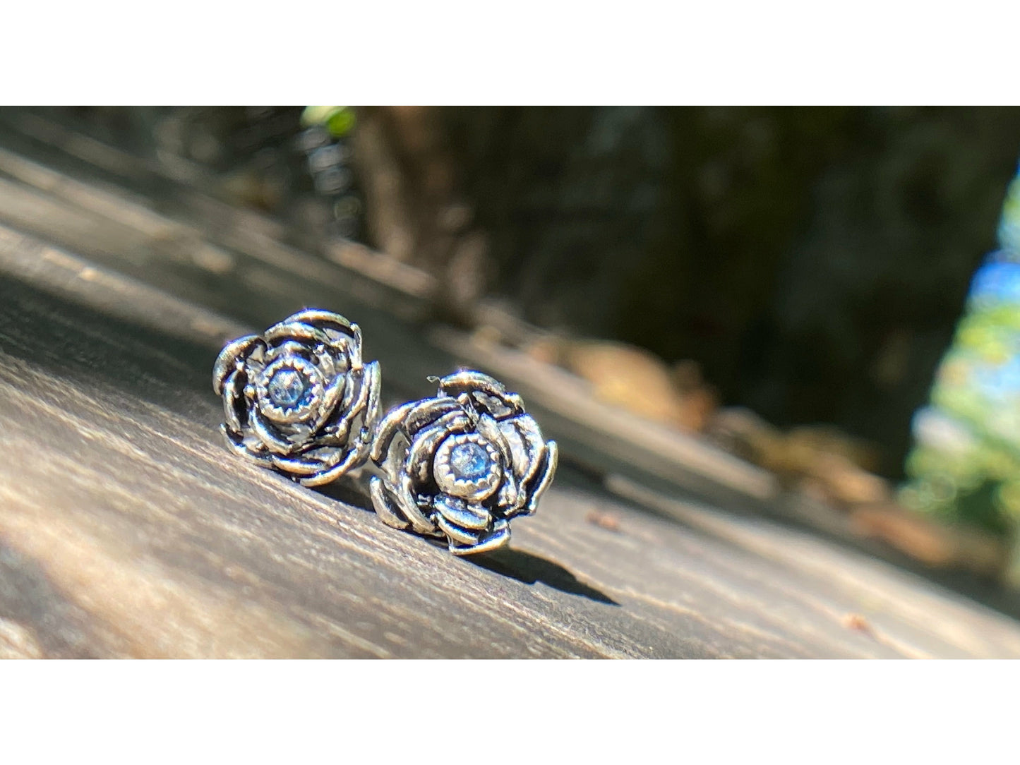 Rose wrapped silver around a small sapphire looking like the center of the bloom.