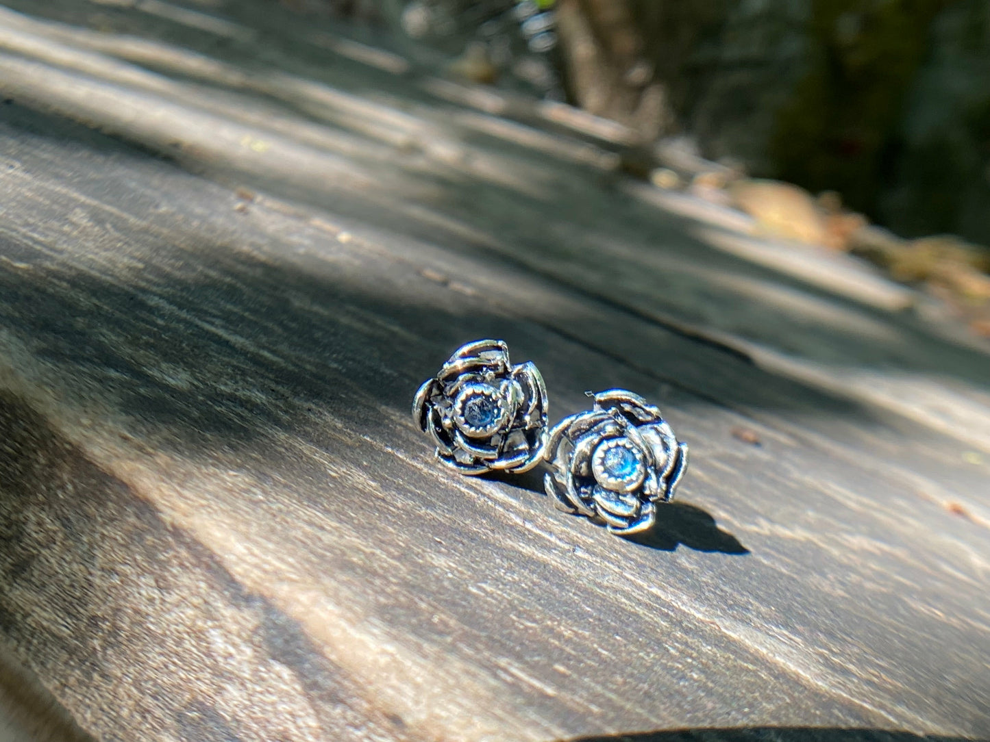 Rose wrapped silver around a small sapphire looking like the center of the bloom.