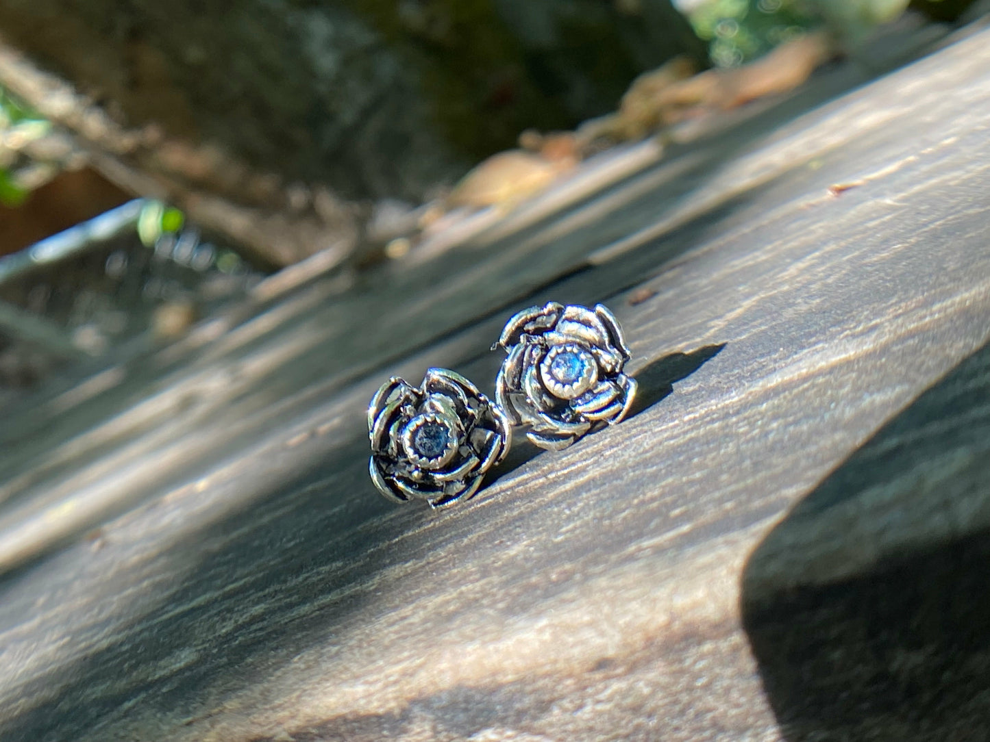Rose wrapped silver around a small sapphire looking like the center of the bloom.