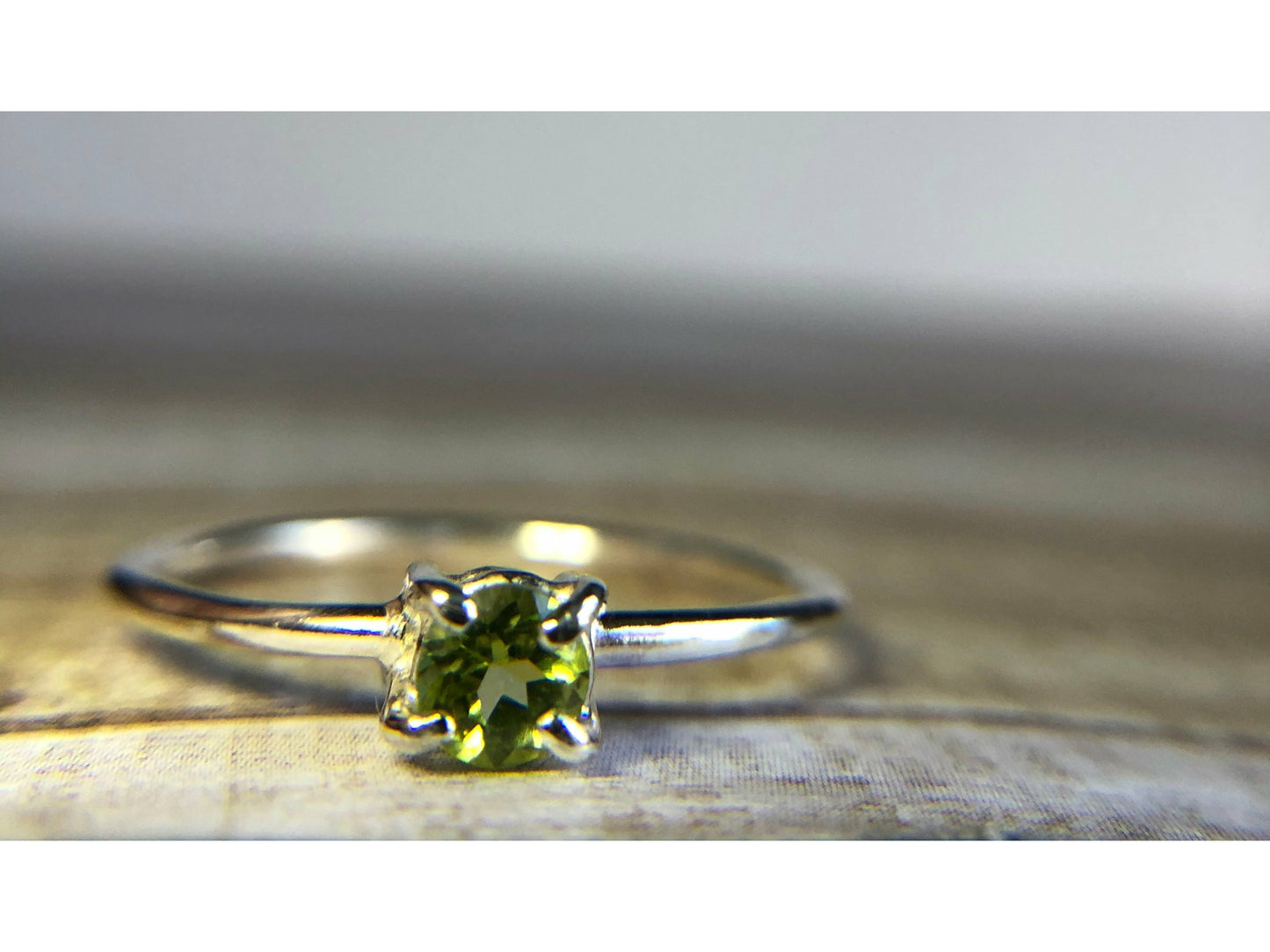 small green gemstone with simple band connecting to left and right side of stone.