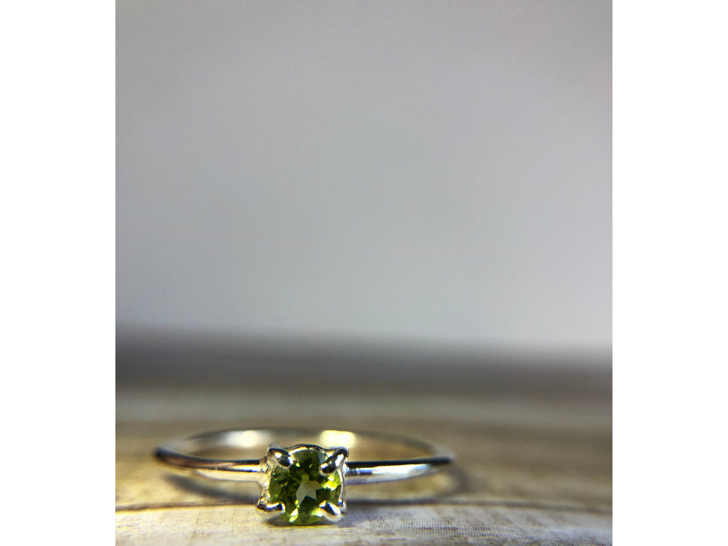 small green gemstone with simple band connecting to left and right side of stone.