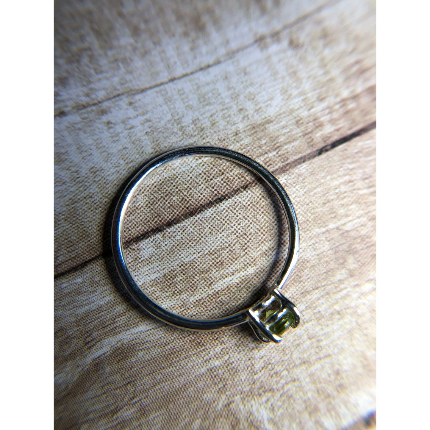 small green gemstone with simple band connecting to left and right side of stone.