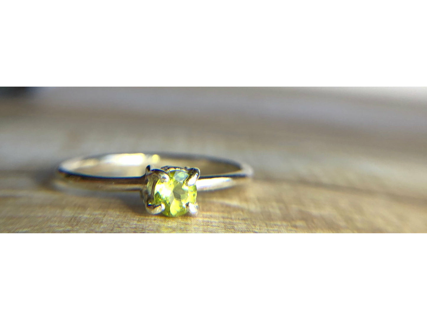 small green gemstone with simple band connecting to left and right side of stone.