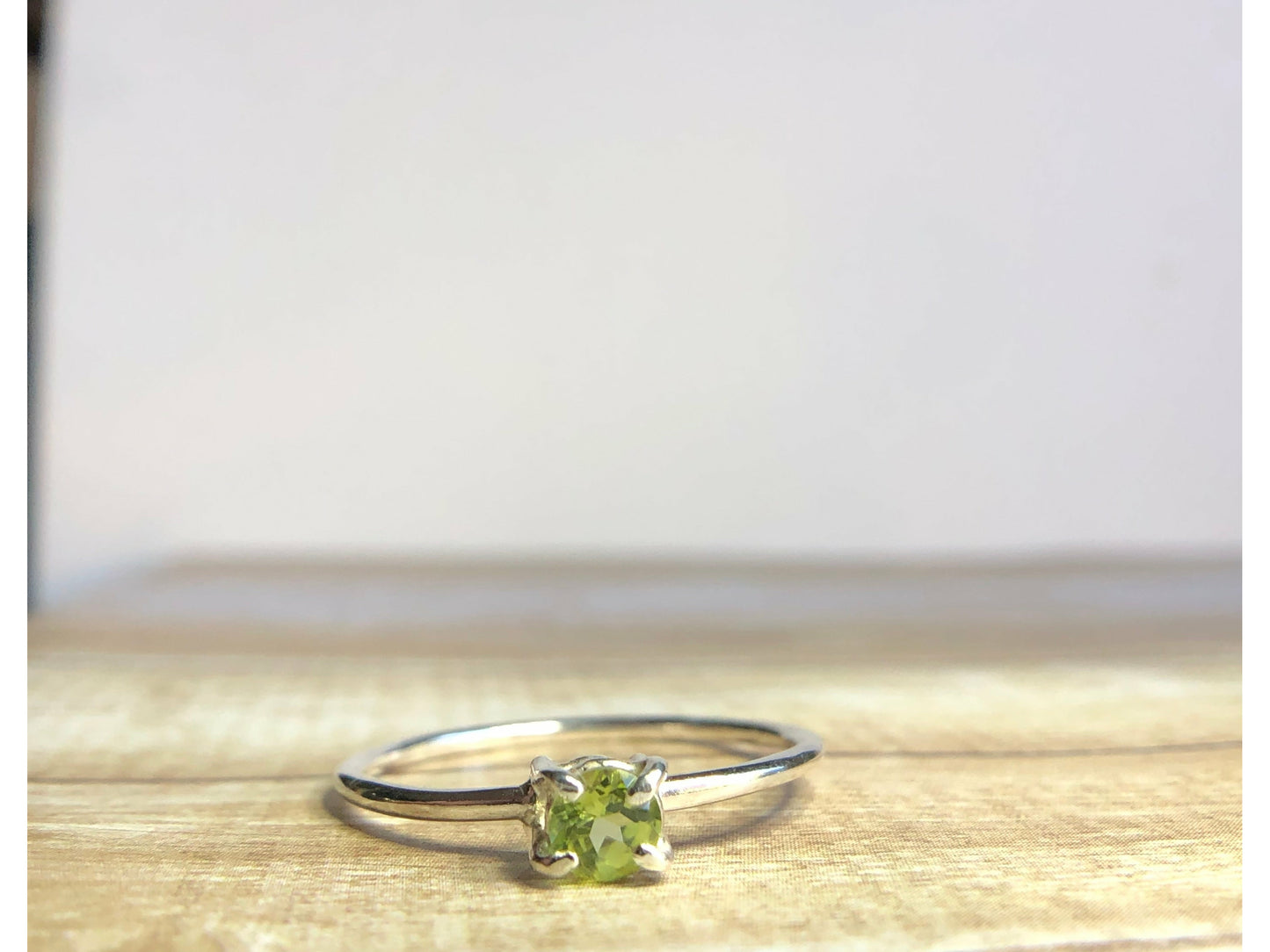 small green gemstone with simple band connecting to left and right side of stone.