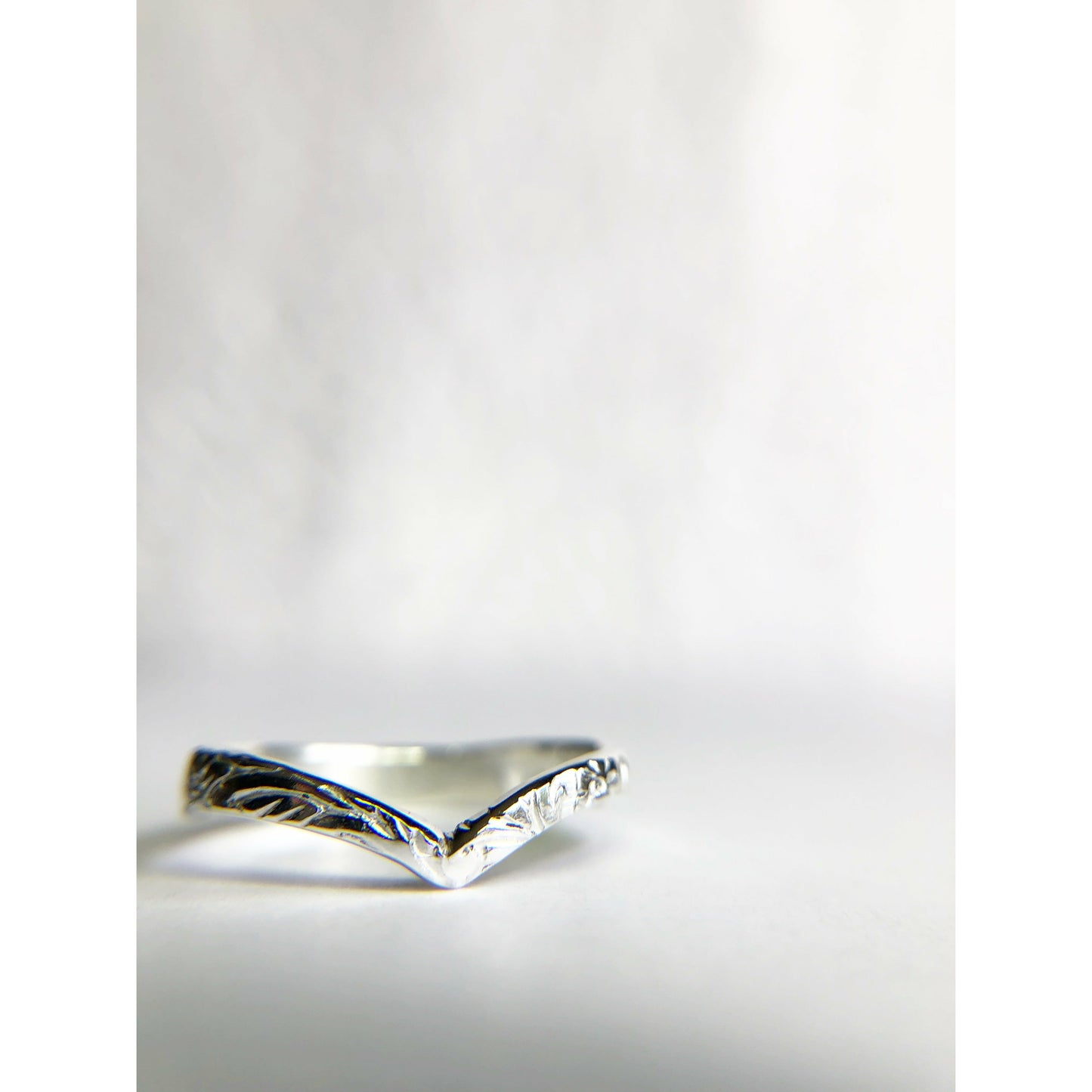 Patterned silver ring with chevron shape.
