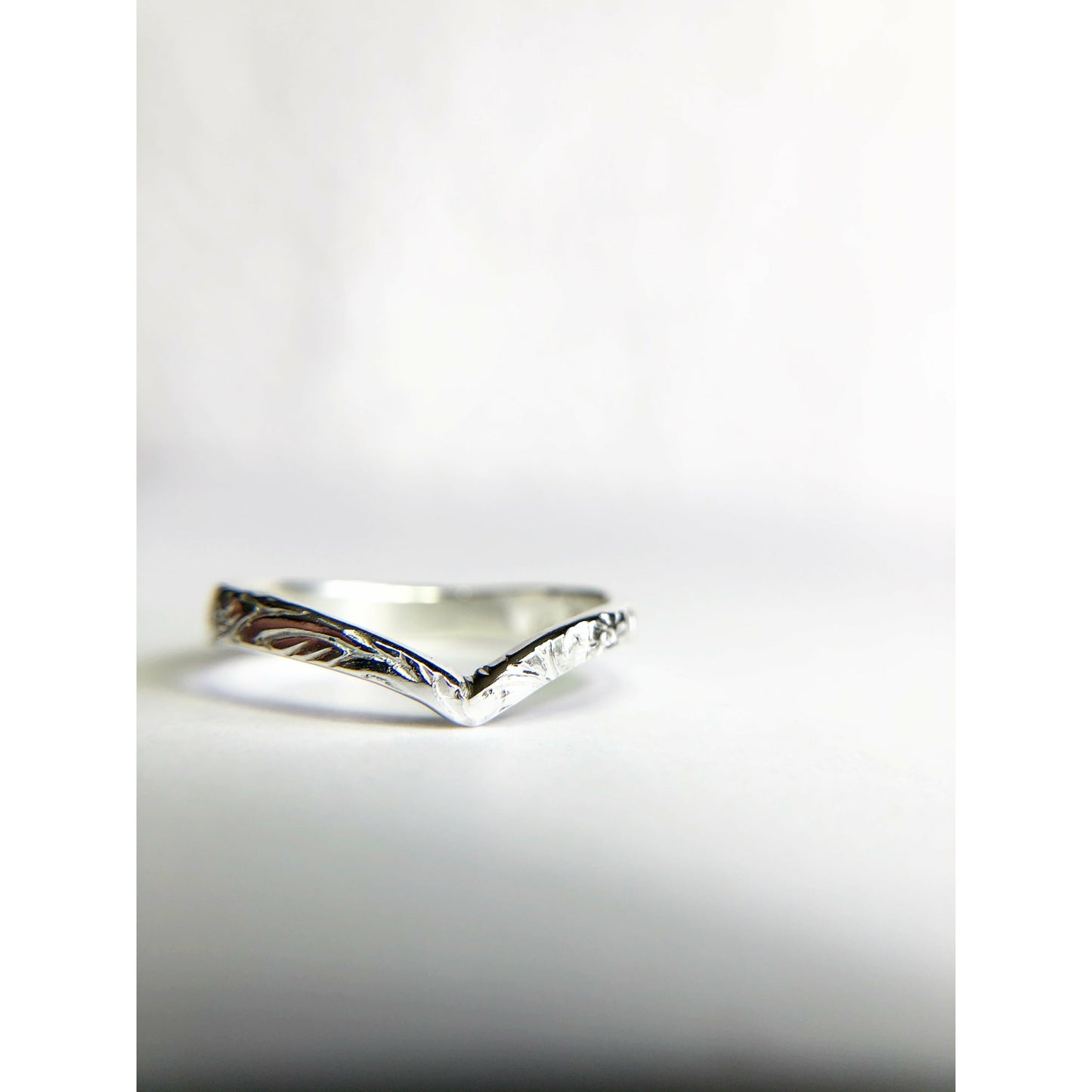Patterned silver ring with chevron shape.