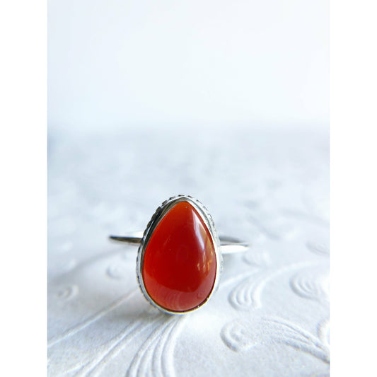 Pear shaped red ring with open back bezel, bezel mounts to the left and right side of the stone.