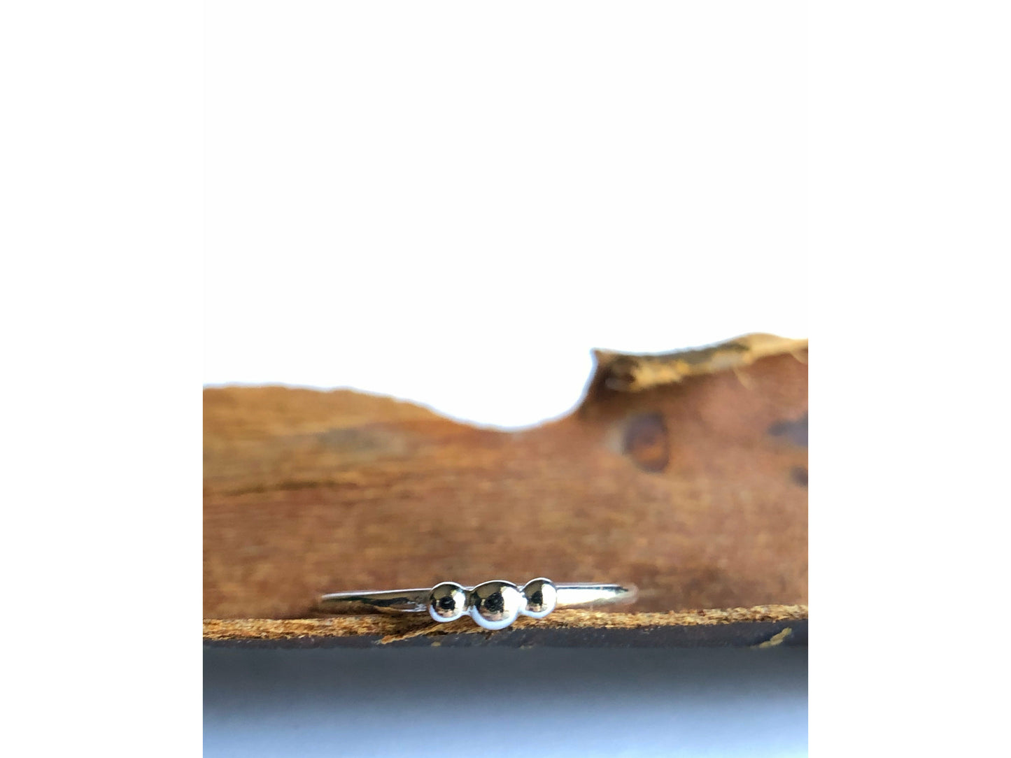 small dots of silver three in total as the focal of this rounded band ring.
