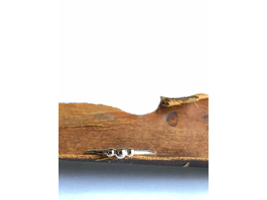 small dots of silver three in total as the focal of this rounded band ring.