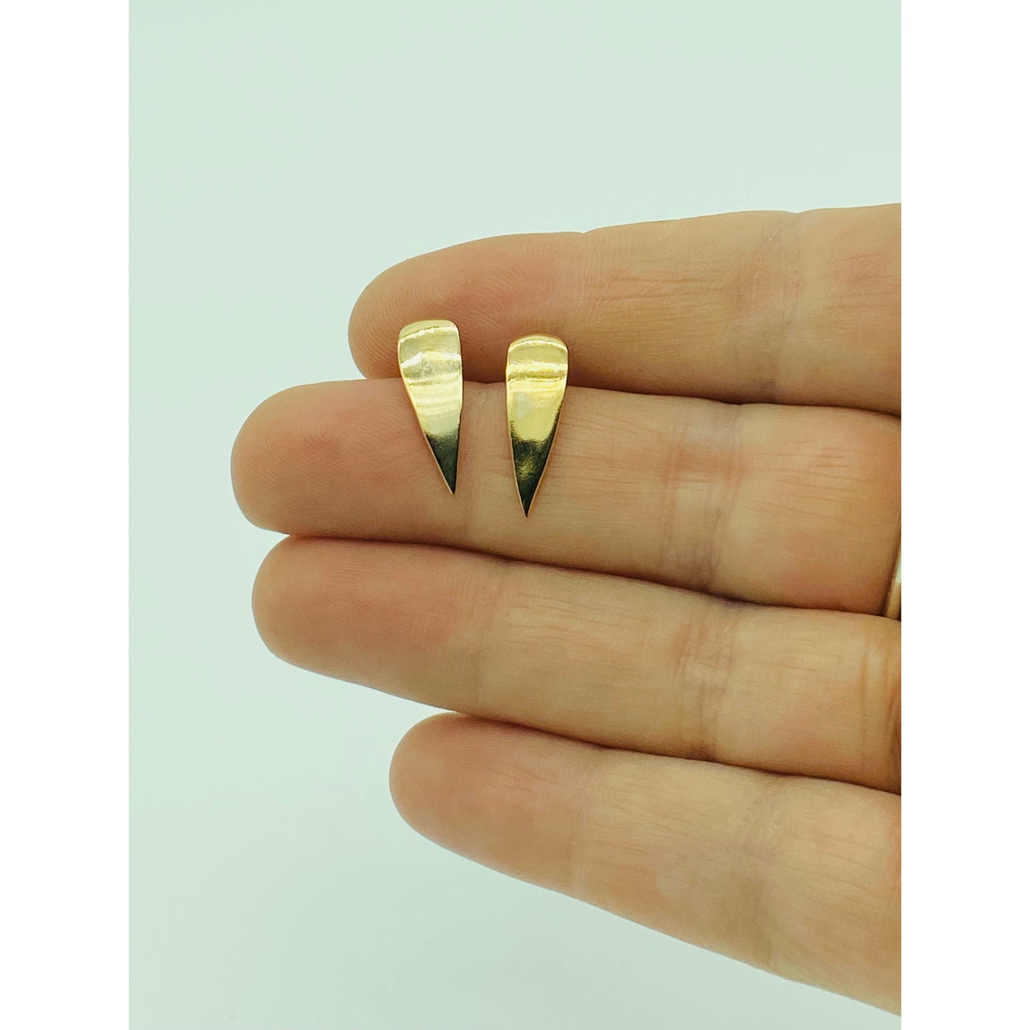 Gold spike earrings with point facing down.