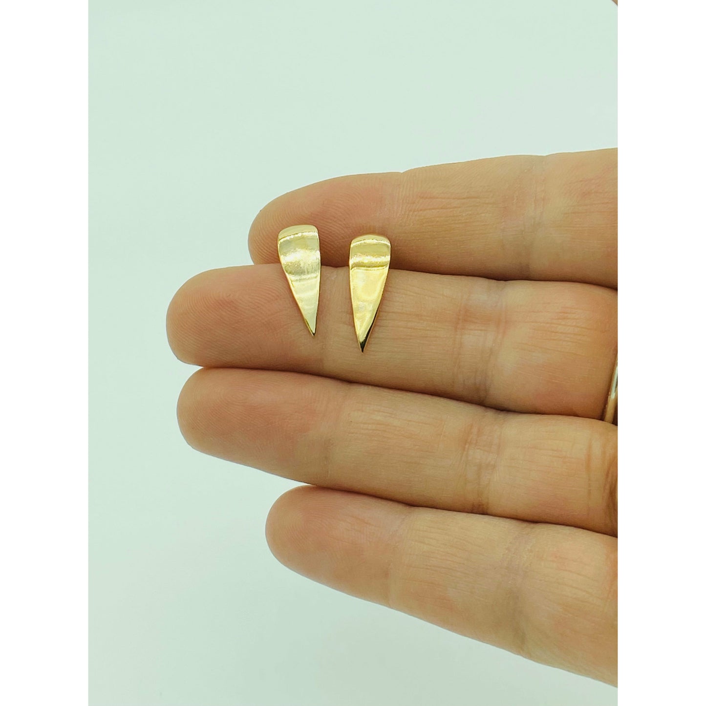 Gold spike earrings with point facing down.