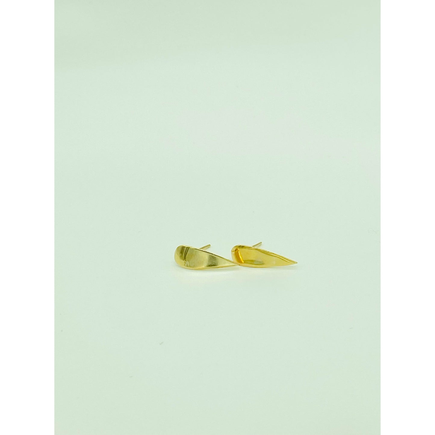 Gold spike earrings with point facing down.