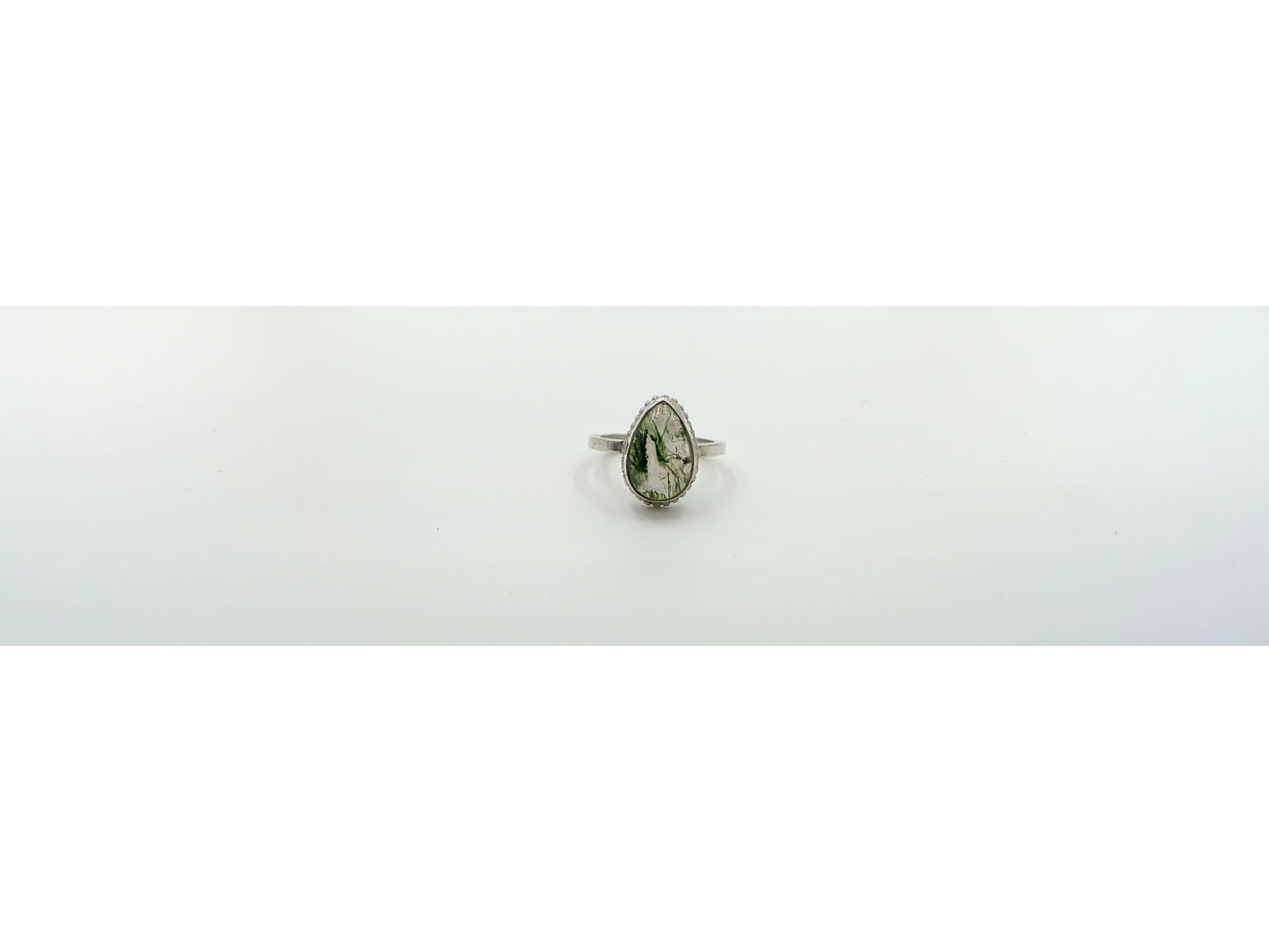 small green moss suspended in quartz, open bezel so light shines through mounted on a rounded simple band.