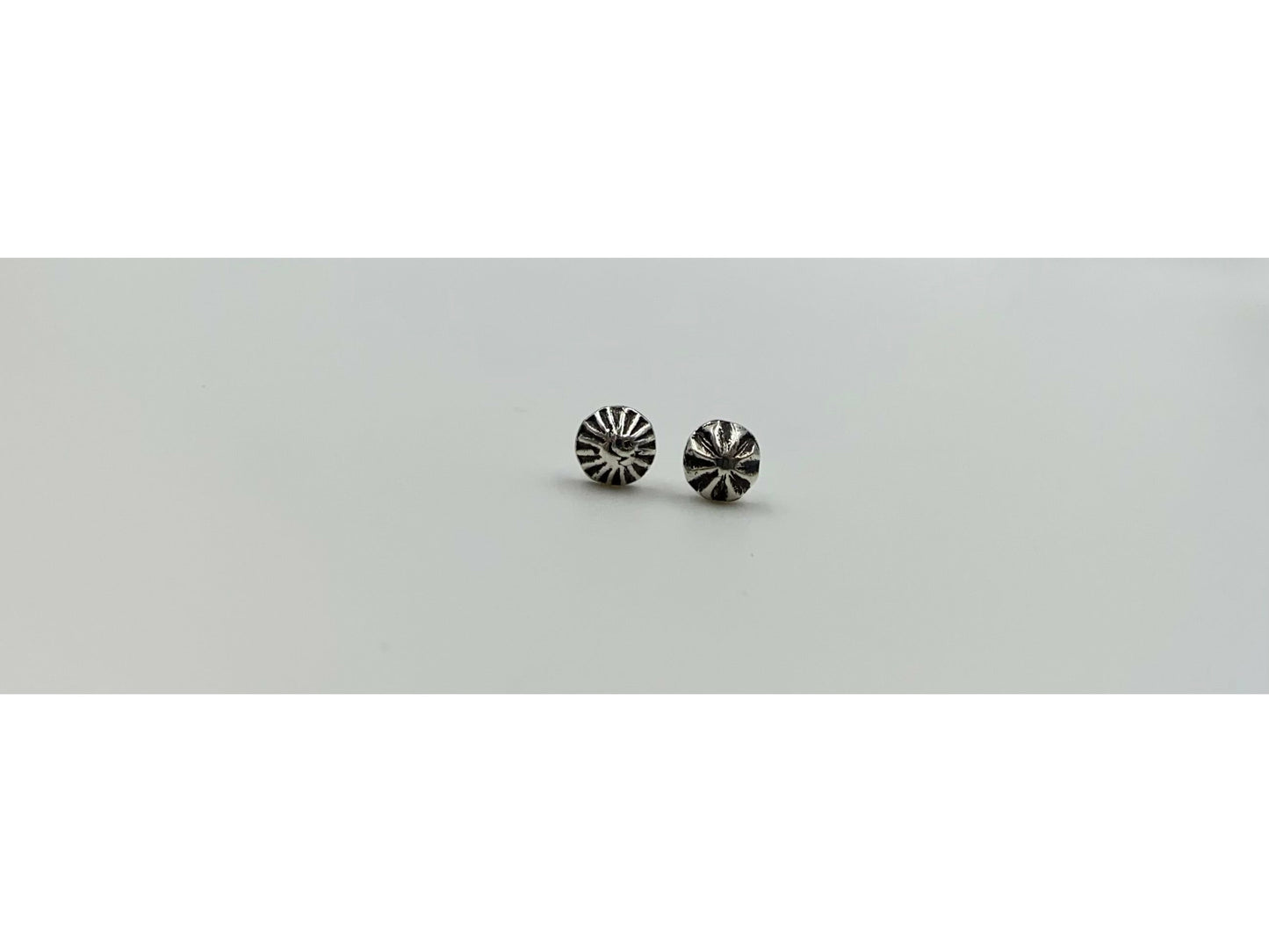 Two mismatched silver earrings, one with a bullet form and one with a spiral.