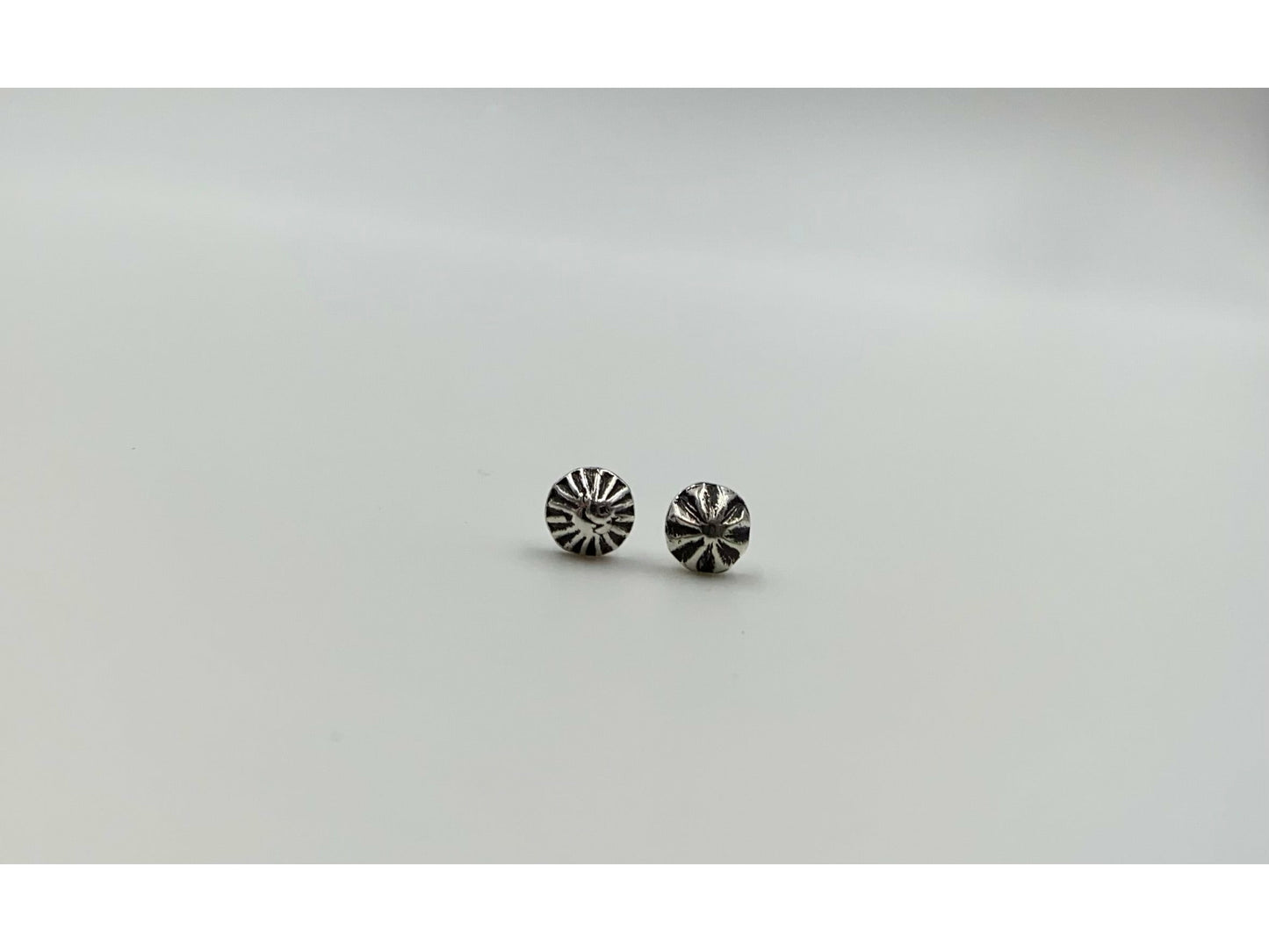 Two mismatched silver earrings, one with a bullet form and one with a spiral.
