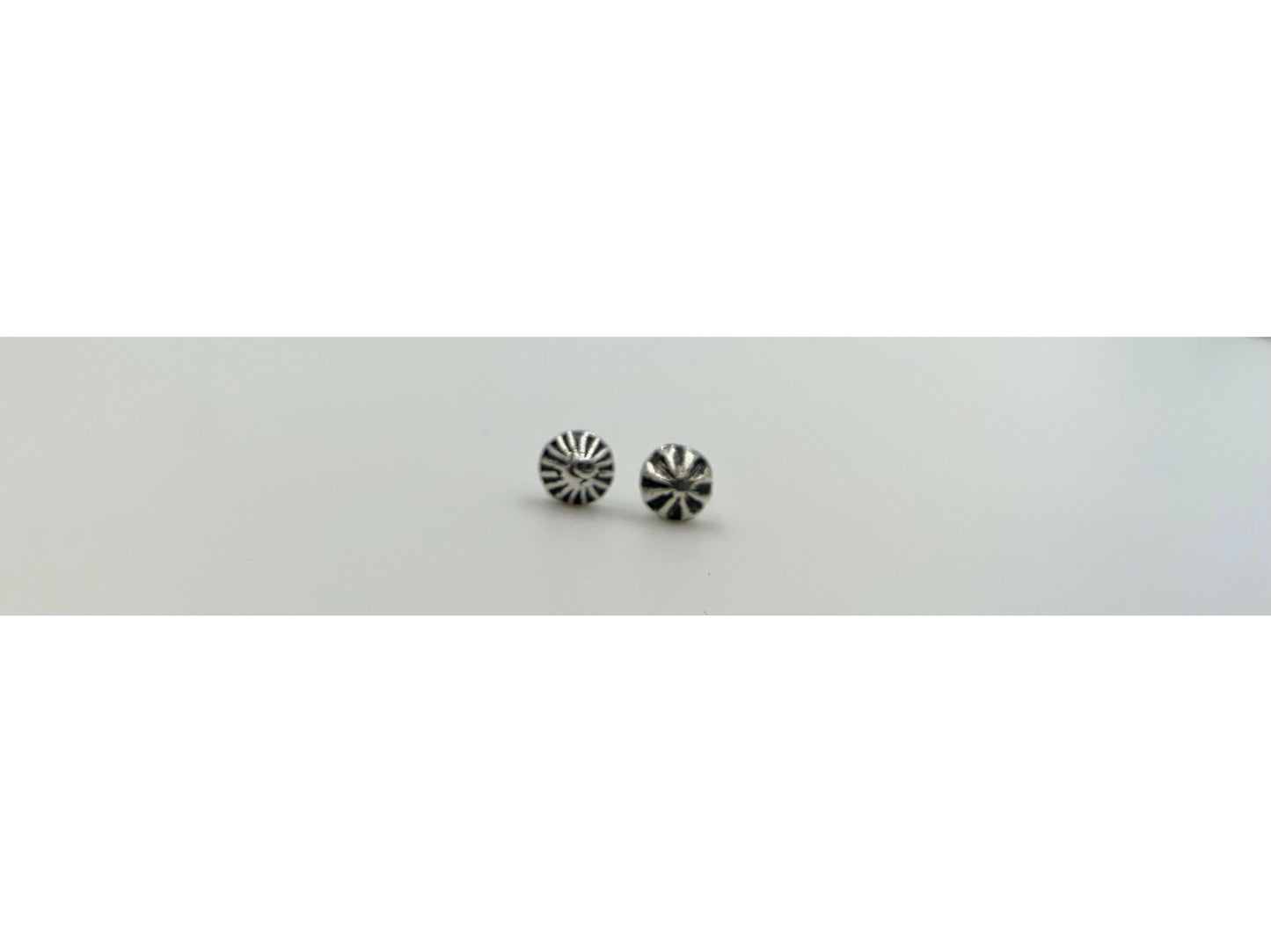 Two mismatched silver earrings, one with a bullet form and one with a spiral.