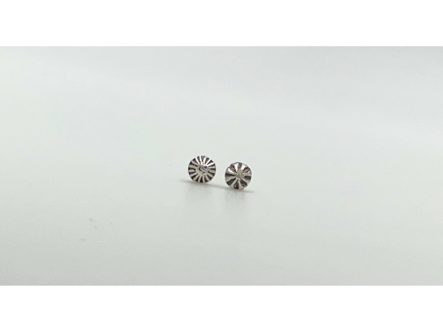 Two mismatched silver earrings, one with a bullet form and one with a spiral.