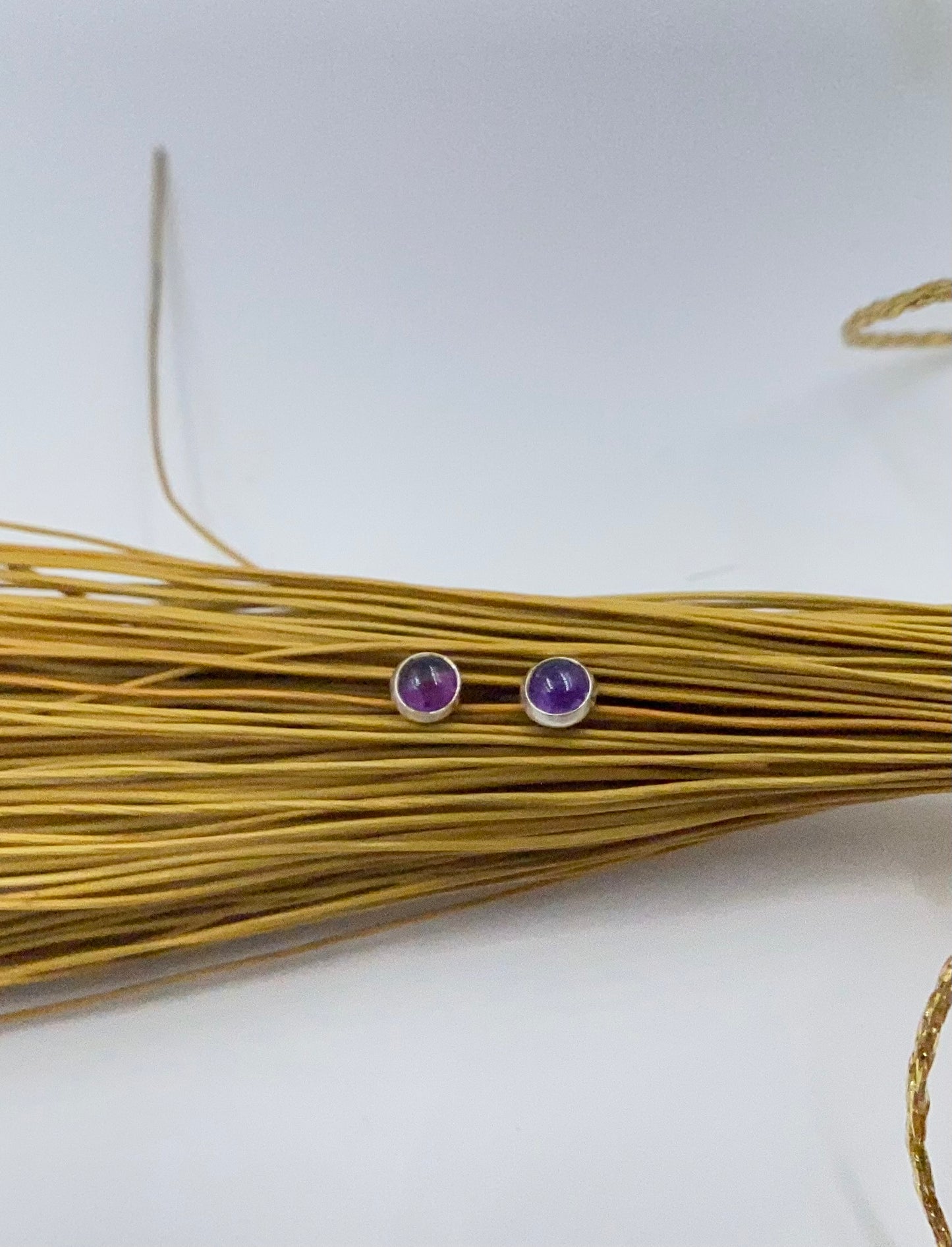 Small amethyst studs with closed back bezel.